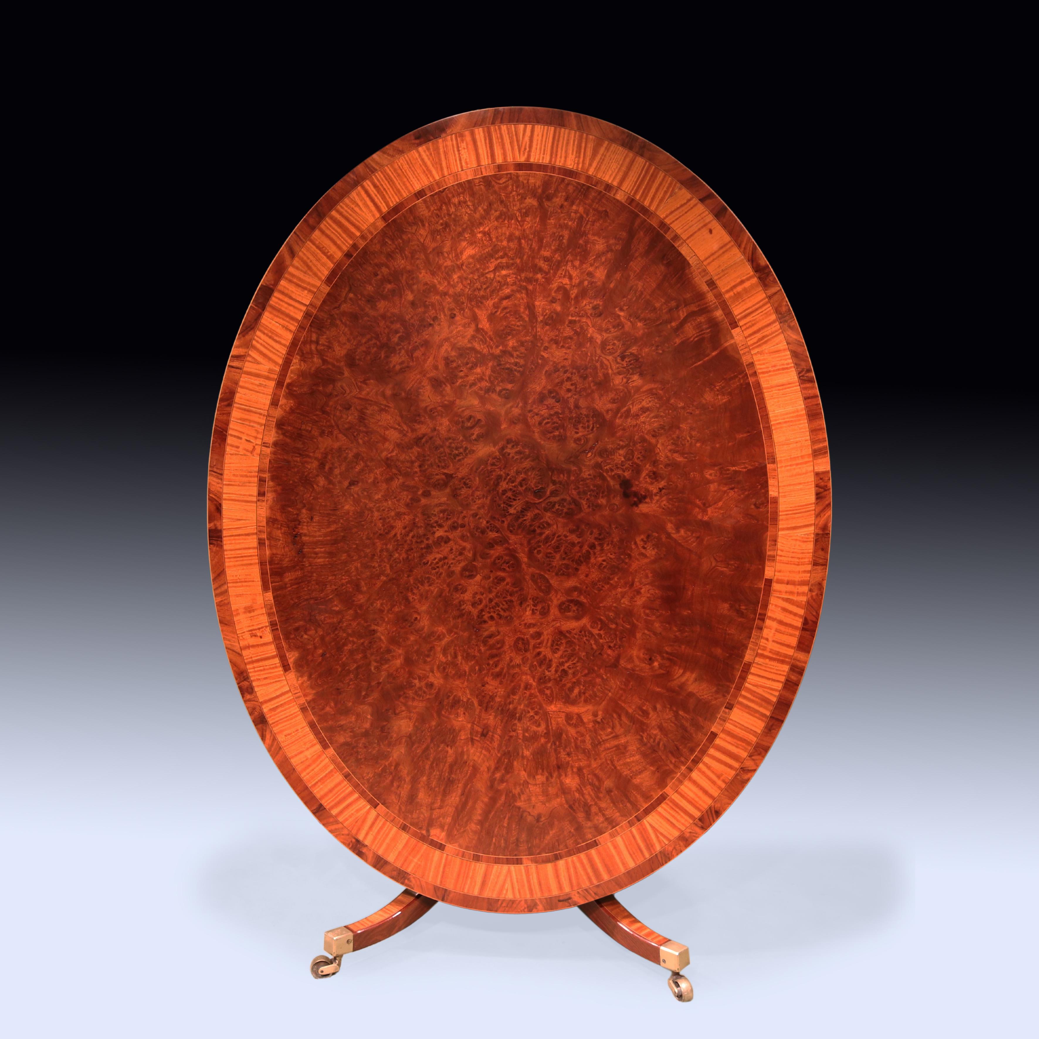 A fine quality late 18th Century Sheraton period oval Breakfast Table veneered in unusual mahogany with coromandel & satinwood crossbanded edge, supported on baluster turned stem ending on satinwood panelled 4-splay base retaining original brass