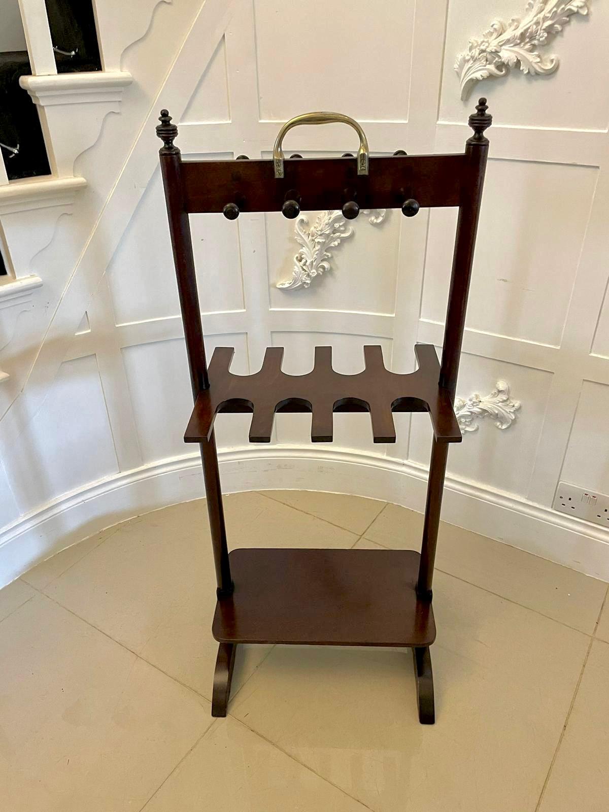 Antique George III quality mahogany boot rack having the original brass carrying handle and turned mahogany pegs, double sided boot stand supported by turned mahogany columns standing on shaped feet united by a shaped mahogany undertier. 

A