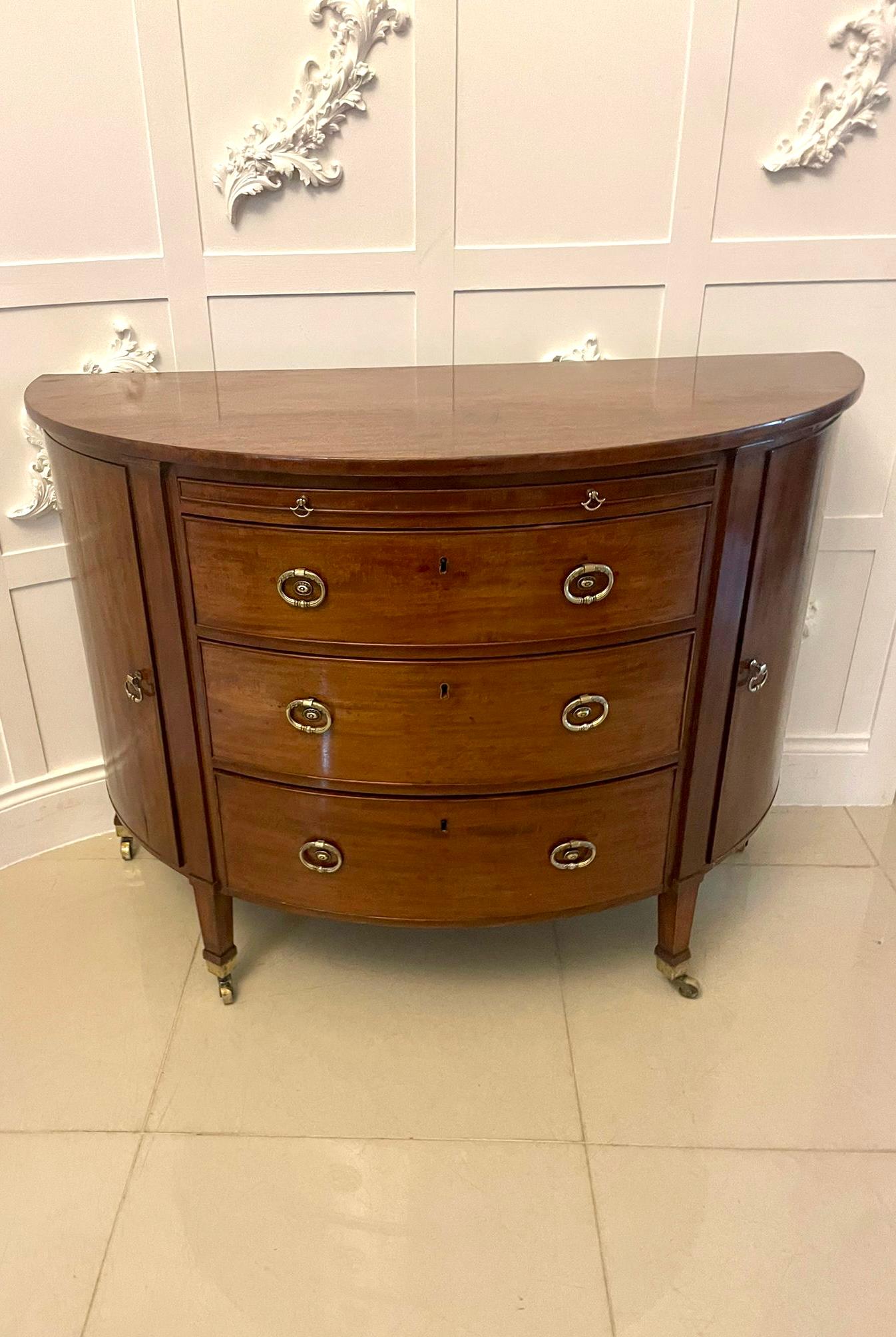 Antique George III quality mahogany demi lune shaped commode/chest of drawers having a quality mahogany demi lune shaped top above a blushing slide and three mahogany cockbeeded oak lined drawers with ornate brass handles flanked by cupboard doors
