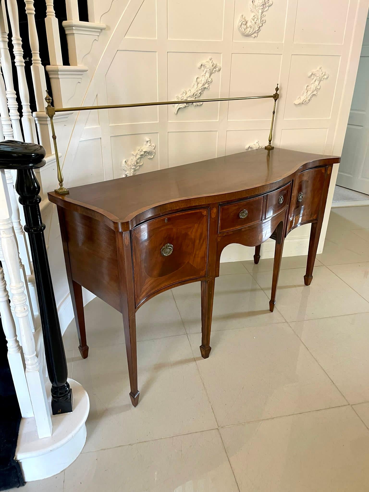 Antique George III quality mahogany inlaid serpentine shaped sideboard having a quality mahogany serpentine shaped top with satinwood crossbanding and the original brass rail above a bow fronted shaped drawer with satinwood crossbanding, original