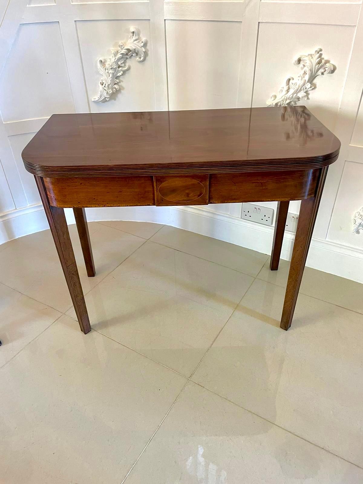 Antique George III quality mahogany tea table having a quality mahogany fold over top with a reeded edge opening to reveal a polished interior, shaped mahogany frieze with satinwood inlay standing on four mahogany tapering reeded legs 

A classic