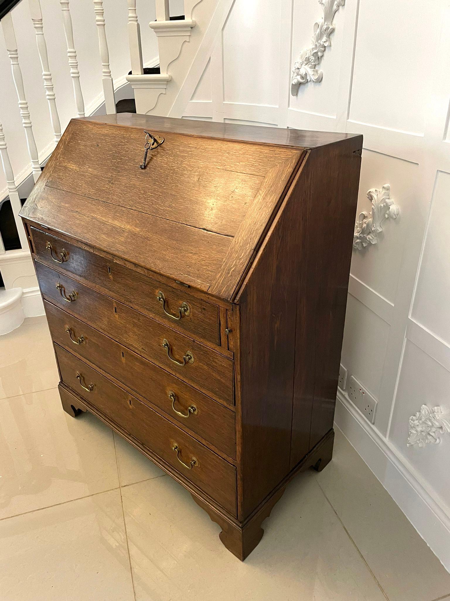 Antique George III quality oak bureau having a quality oak fall opening to reveal a fitted interior consisting of six small drawers with original brass handles, six pigeon holes and a centre door 
above four long cockbeeded drawers with original