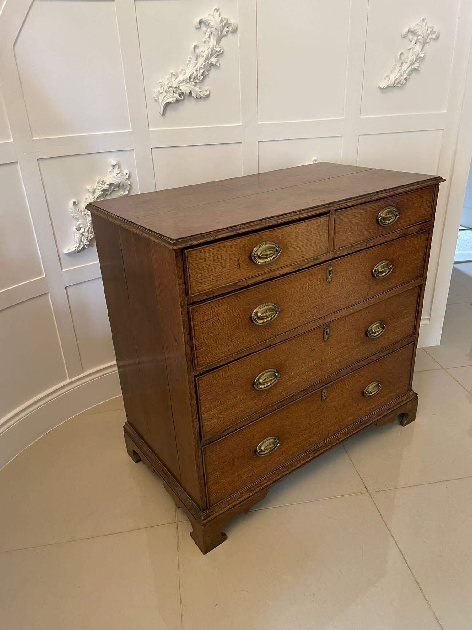 Antique George III quality oak chest of drawers having a quality rectangular shaped oak top with a thumb moulded edge above two short and three long cockbeeded drawers with original oval brass handles standing on original shaped bracket feet