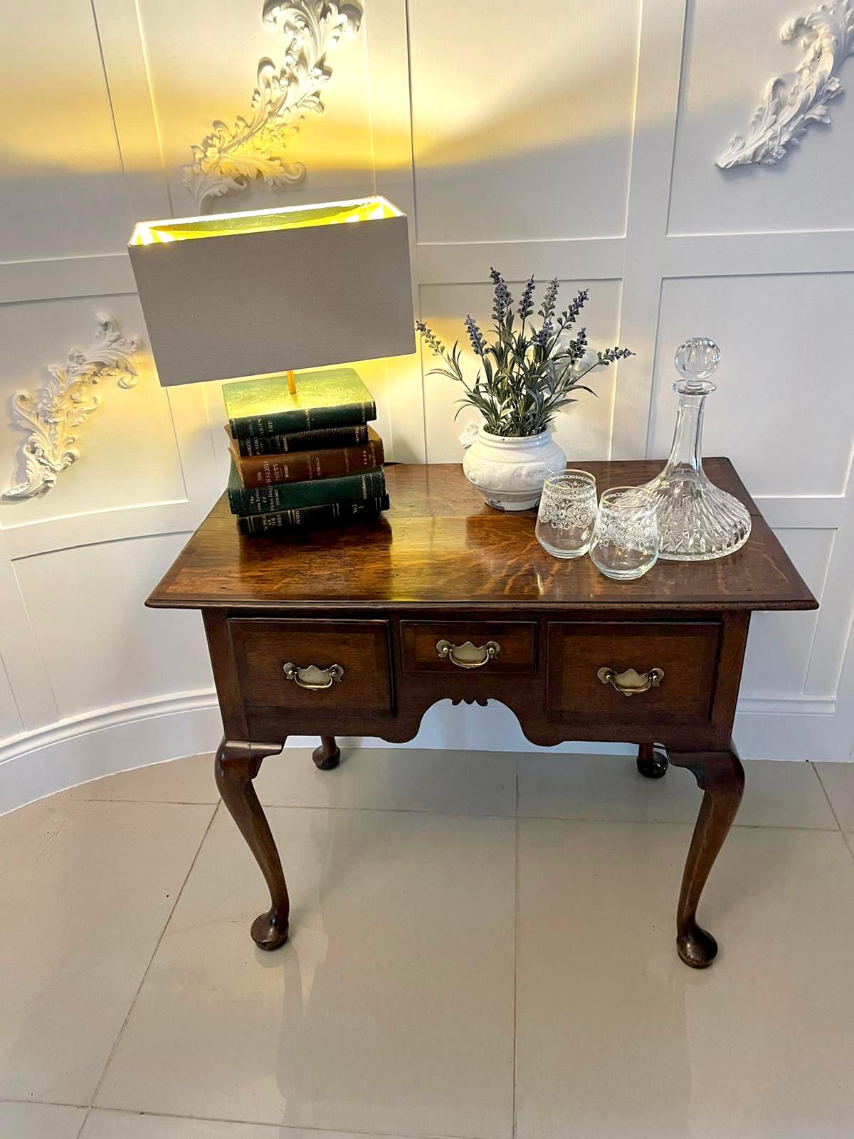 Antique George III quality oak lowboy having a quality oak rectangular shaped top with mahogany crossbanding above three oak drawers with mahogany crossbanding and original brass handles, shaped frieze and standing on four shaped cabriole legs with