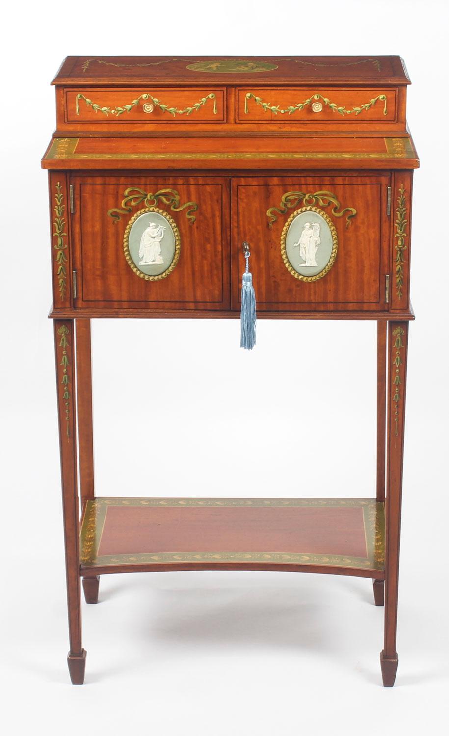 A beautiful antique George III freestanding satinwood cheveret, early 19th century in date.

This superb piece features attractive hand painted decoration of garlands, ribbons and bell flowers, in the manner of Angelica Kauffman, with green oval