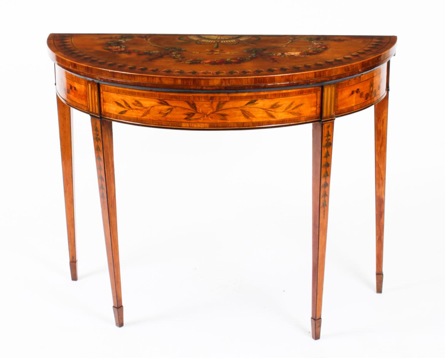 This is a beautiful antique hand painted Goerge III satinwood demi-lune card table, circa 1800 in date and decorated throughout with hand painted floral, foliate and ribbon-tied flowering swags in the manner of Angelica Kauffman.

The folding top