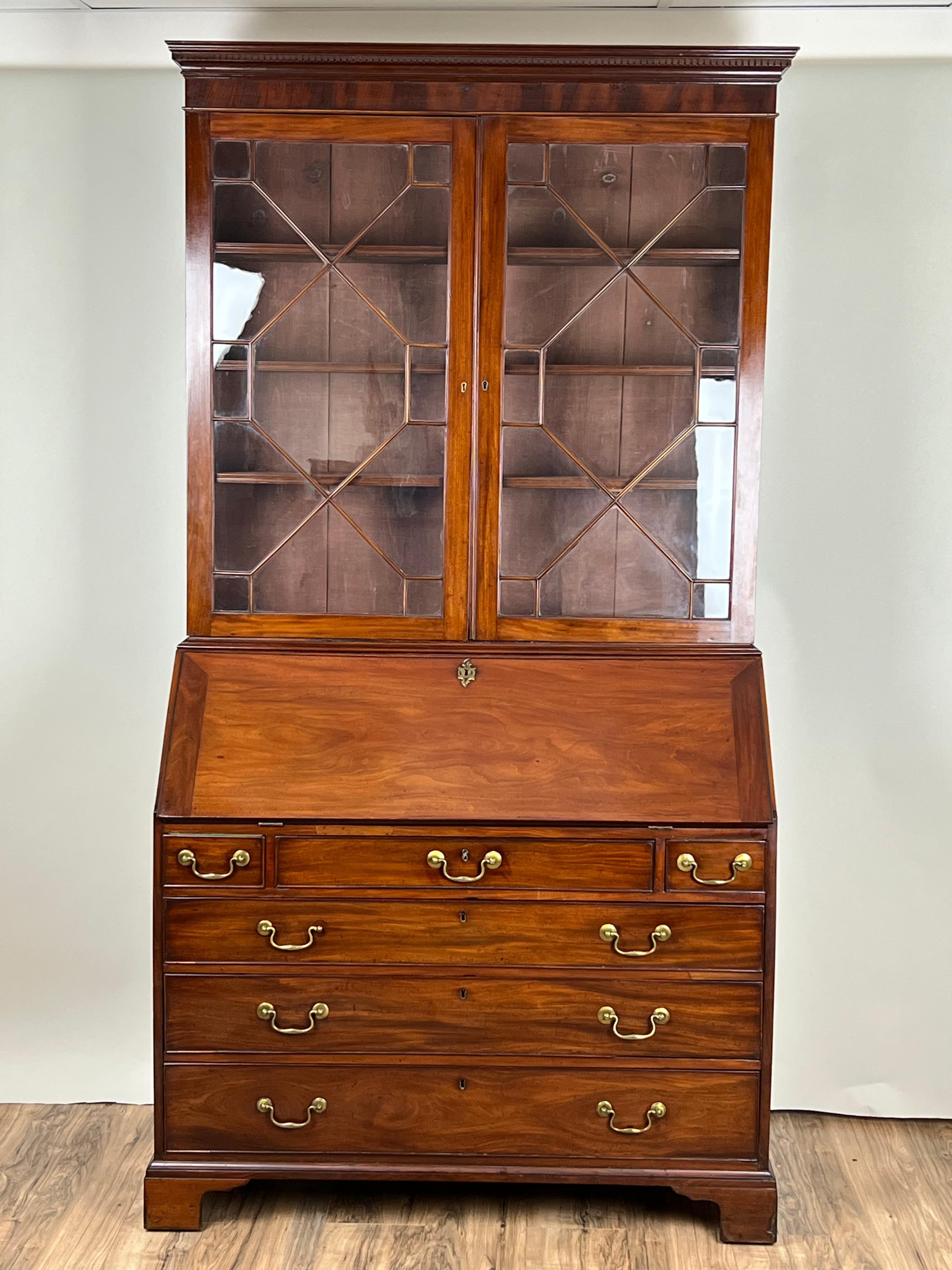 Questo segretario con libreria di Giorgio III della fine del XVIII secolo è un mobile inglese bello e versatile. Realizzato in mogano riccamente scolpito, è caratterizzato da una scrivania a ribalta con scomparti interni attrezzati sopra quattro