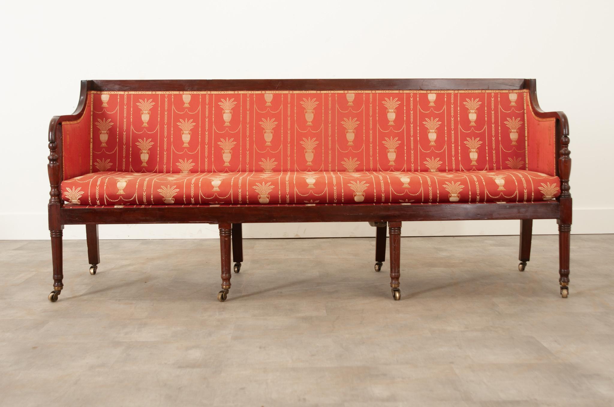 This George III settee is a conversation starter in any space. Crafted with timeless style in mind, it’s upholstery with red silk with an urn and floral motif on meteoric gold silk thread. The fabric is beautifully detailed and in wonderful antique