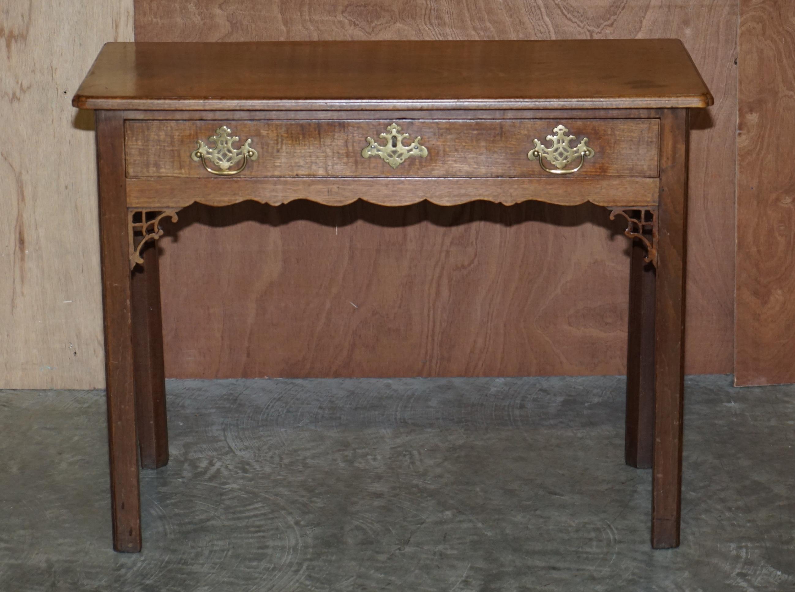 Siamo lieti di offrire in vendita questo eccezionale tavolino a un cassetto in mogano massiccio di George III con finiture originali in ottone e intagli in stile Thomas Chippendale.

Questo pezzo è sublime, pesa circa il doppio di quello che