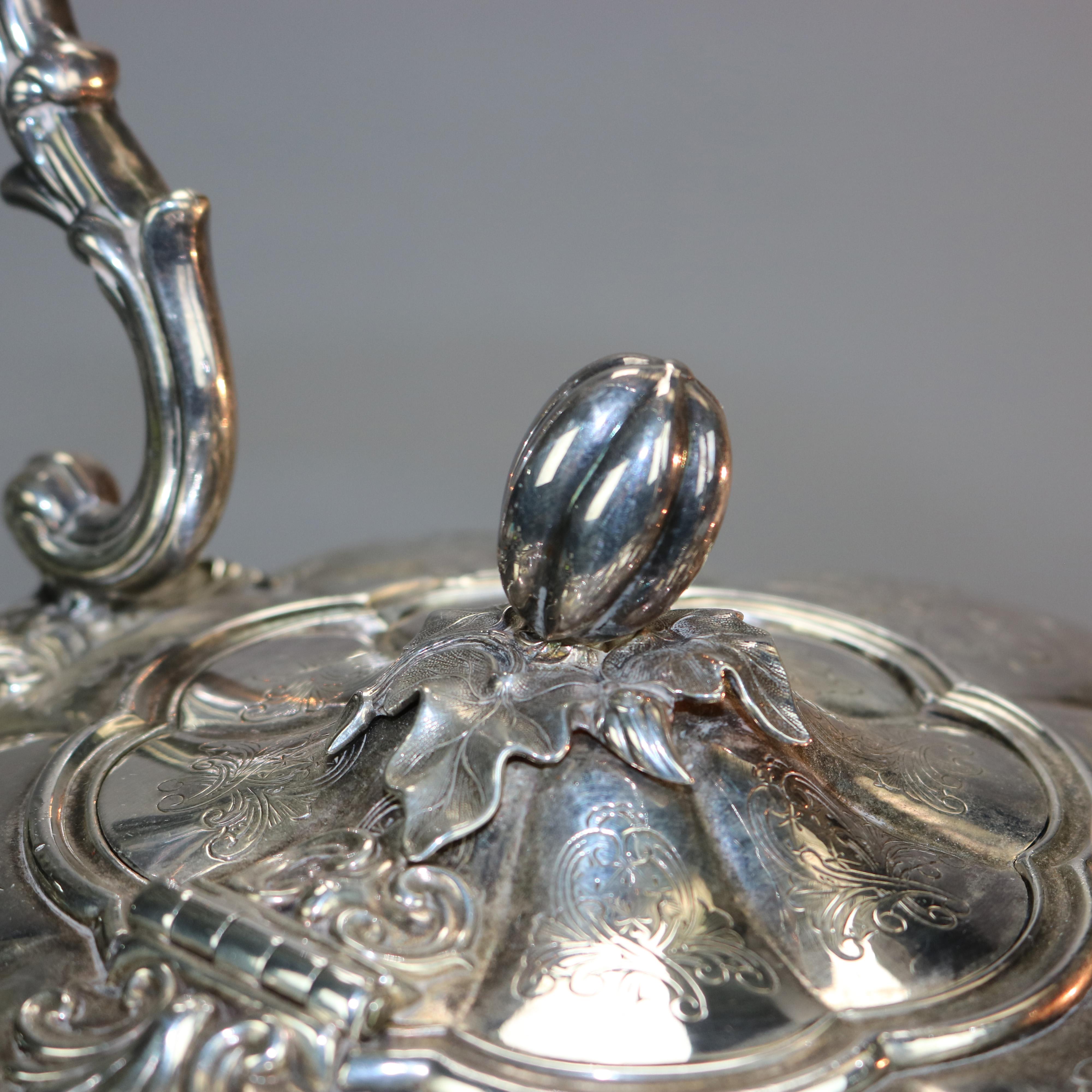 An antique George III silver plate tilting tea pot offers mellon form with foliate and floral engraved decoration, seated on pierced burner with cabriole legs terminating in shell form feet, stamped on base as photographed, c1830

Measures: 14.75