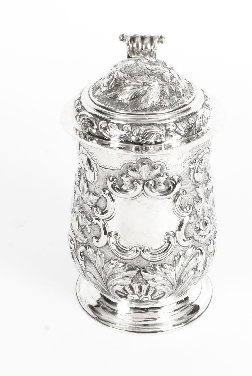 This is a truly wonderful antique English George III sterling silver lidded tankard with hallmarks for London 1774 and the maker's mark of the renowned silversmith, John King.

This magnificent tankard features wonderful embossed floral decorations