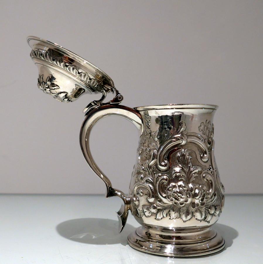 A splendid quality later embellished sterling silver baluster tankard and cover decorated with elegant floral embossing which is the set on a matte background for contrast. The centre front of the body has a stylish cartouche in which sits a hand