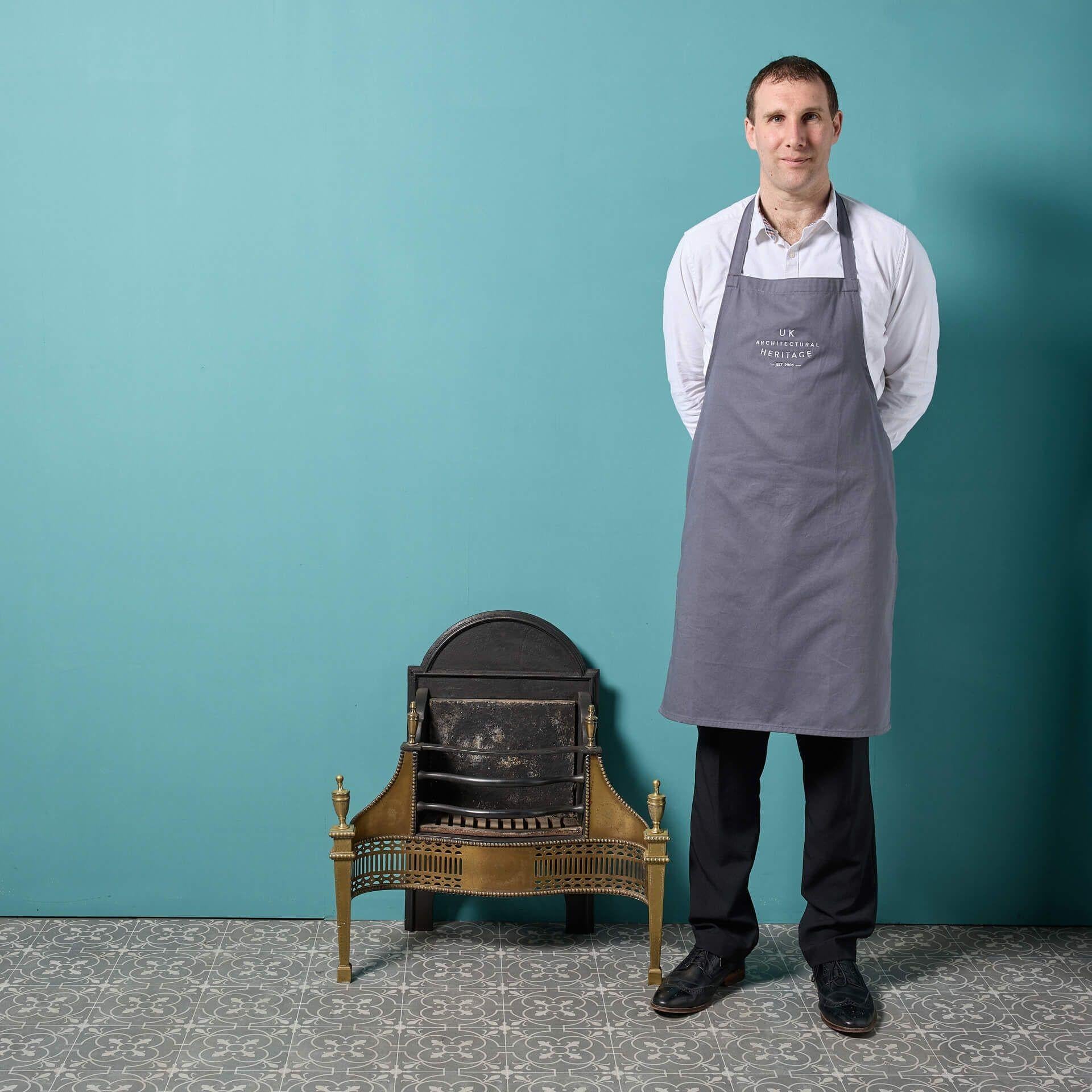 Un'antica griglia da fuoco in ottone e acciaio in stile Giorgio III. Questa griglia per caminetto in ottone lucido inciso dell'inizio del 20° secolo ha un design ornato che sarà il fiore all'occhiello di una grande casa.
Presenta un retro sagomato e