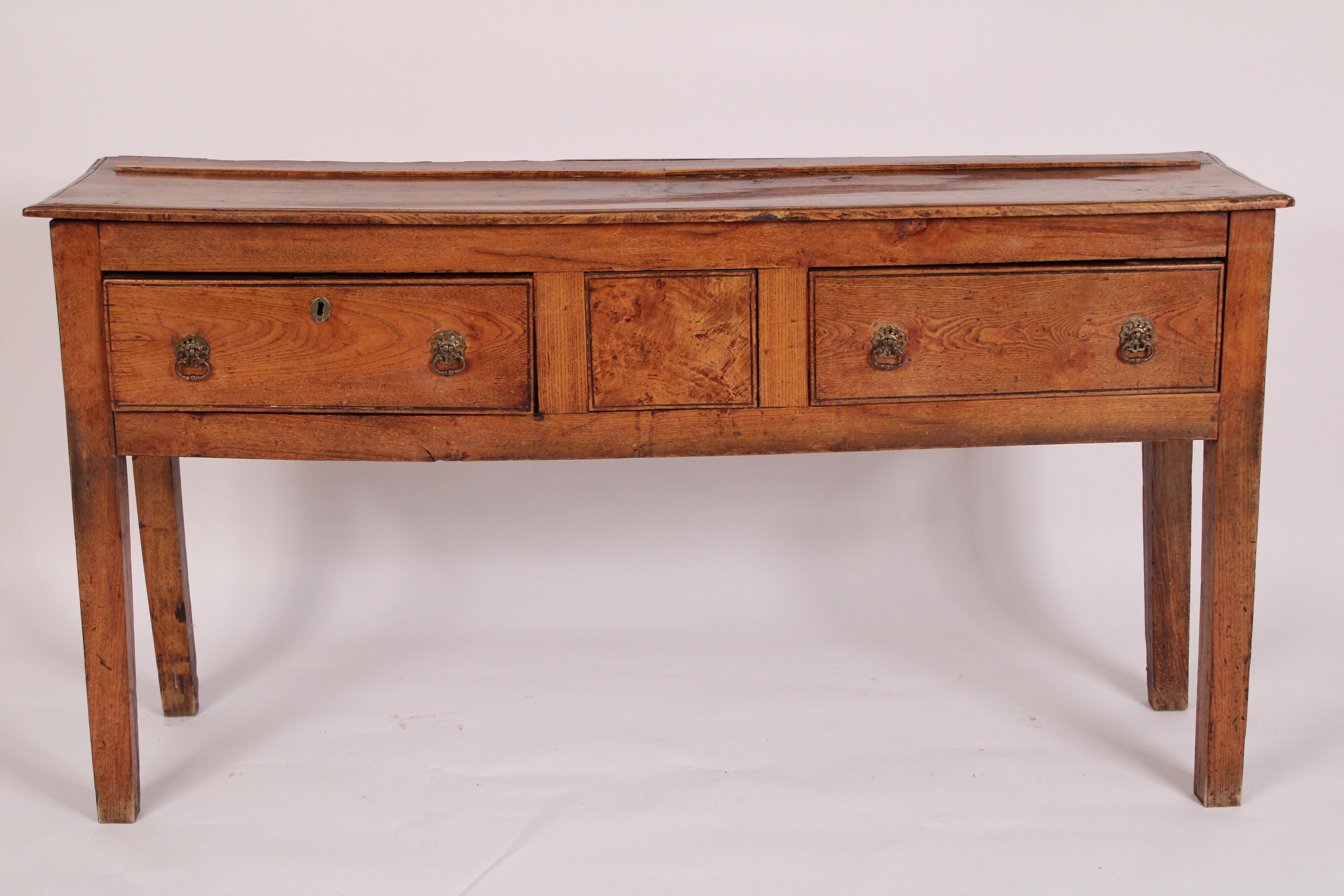 Antique George III style elm wood sideboard. With a rectangular two board top with molded front and side edges, two frieze drawers on either side of a stationary burl elm panel, resting on four square legs. Nice old elm wood color.