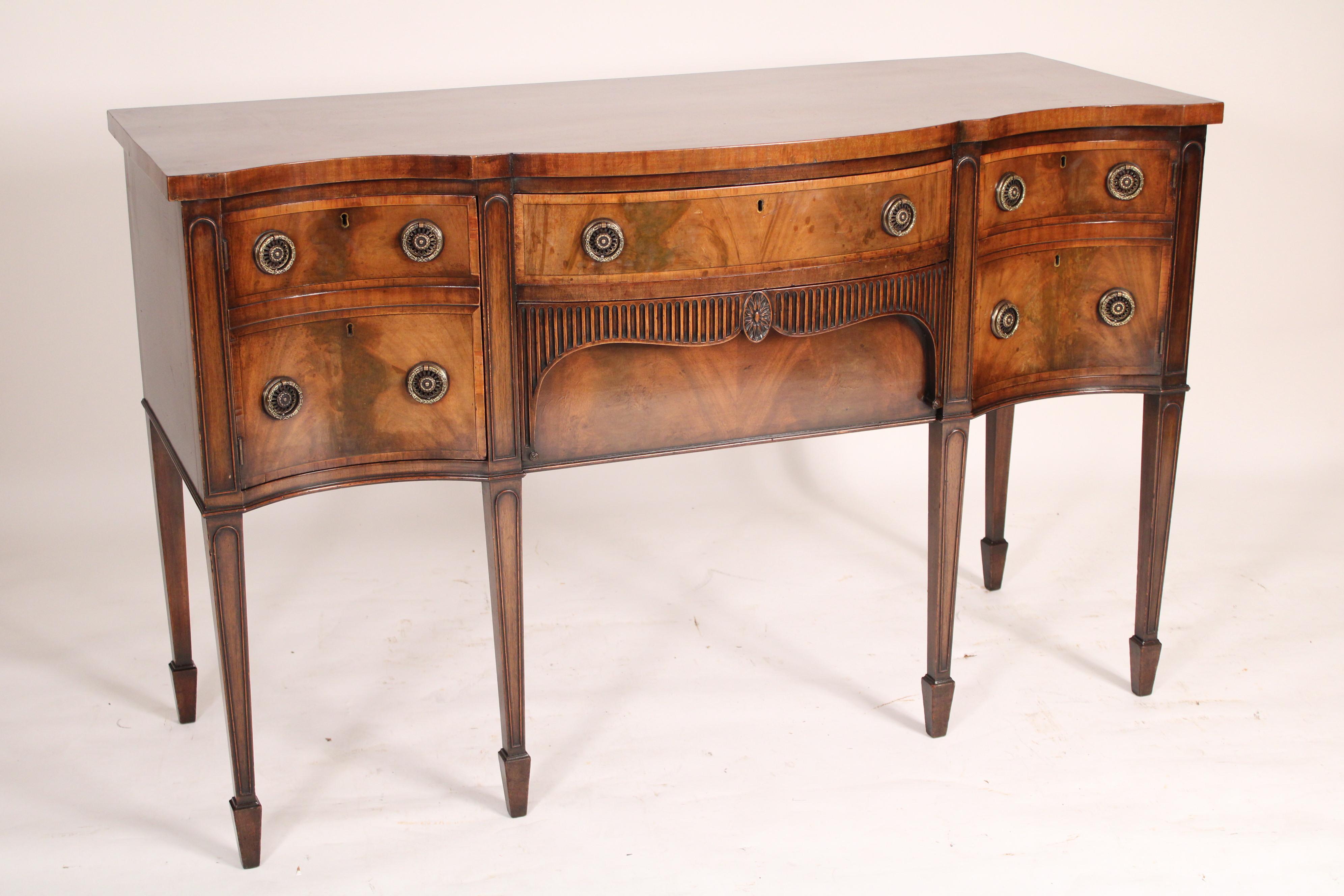 Antique George III style mahogany sideboard, late 19th century. The top with a serpentine shaped front, over two central drawers flanked by two doors all with cross banding, resting on square tapered molded legs ending in spade feet. Exquisite