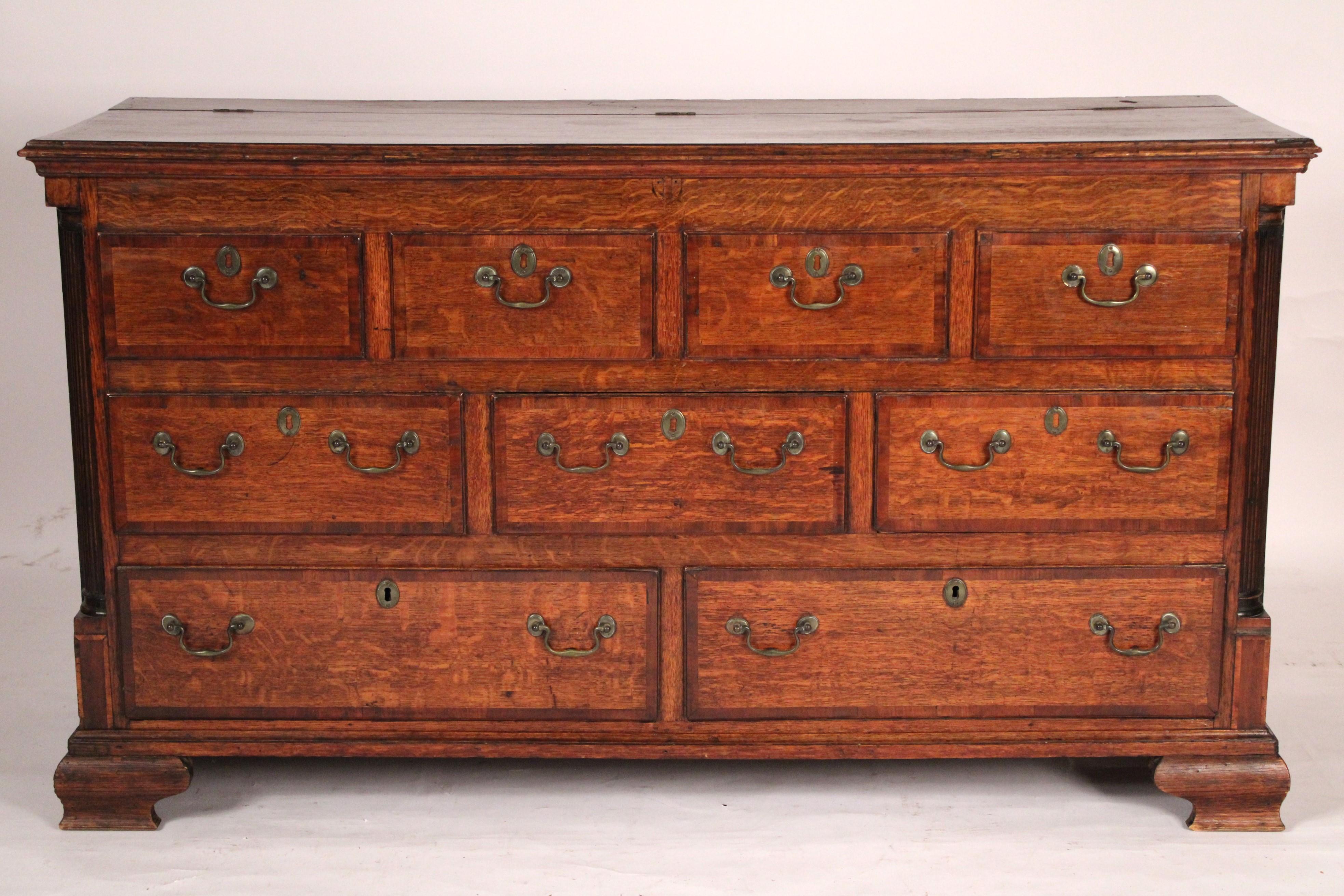 Antique George III style oak sideboard, 19th century. With an overhanging top with thumb molded front and side edges, over 4 quarter sawn oak drawers with mahogany cross banding, over 3 drawers and two bottom drawers, split fluted columns on each
