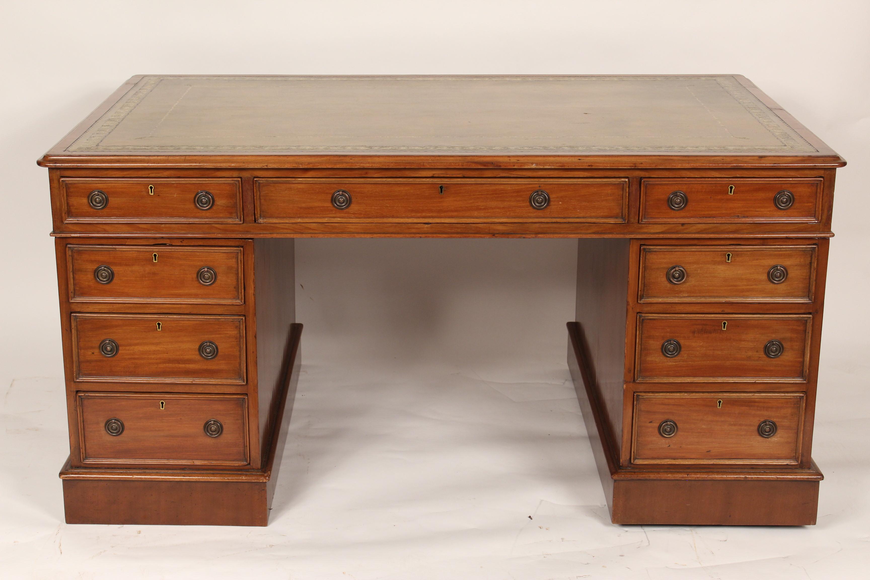 Antique George III style mahogany partners desk with tooled leather top, circa 1890-1910. With drawers on the front side and drawers and doors on the back side. The left and right hand drawers open and close on the back side the center drawer is