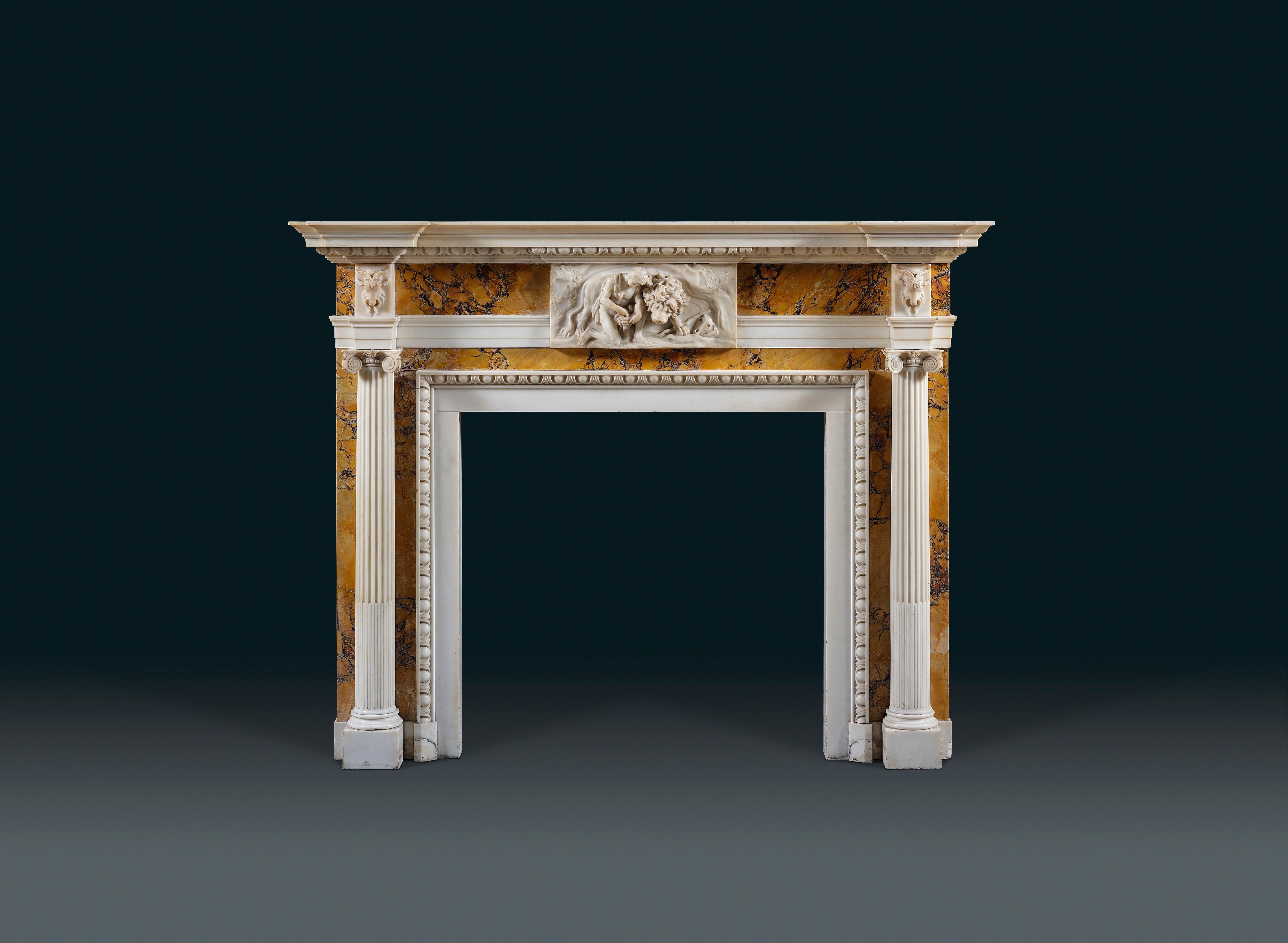 This striking fireplace boasts a finely carved centre tablet depicting a scene from the story of Androcles and the Lion. The frieze is supported by a pair of free-standing, fluted, ionic columns, beneath distinctive goat-mask end-blocks.

The
