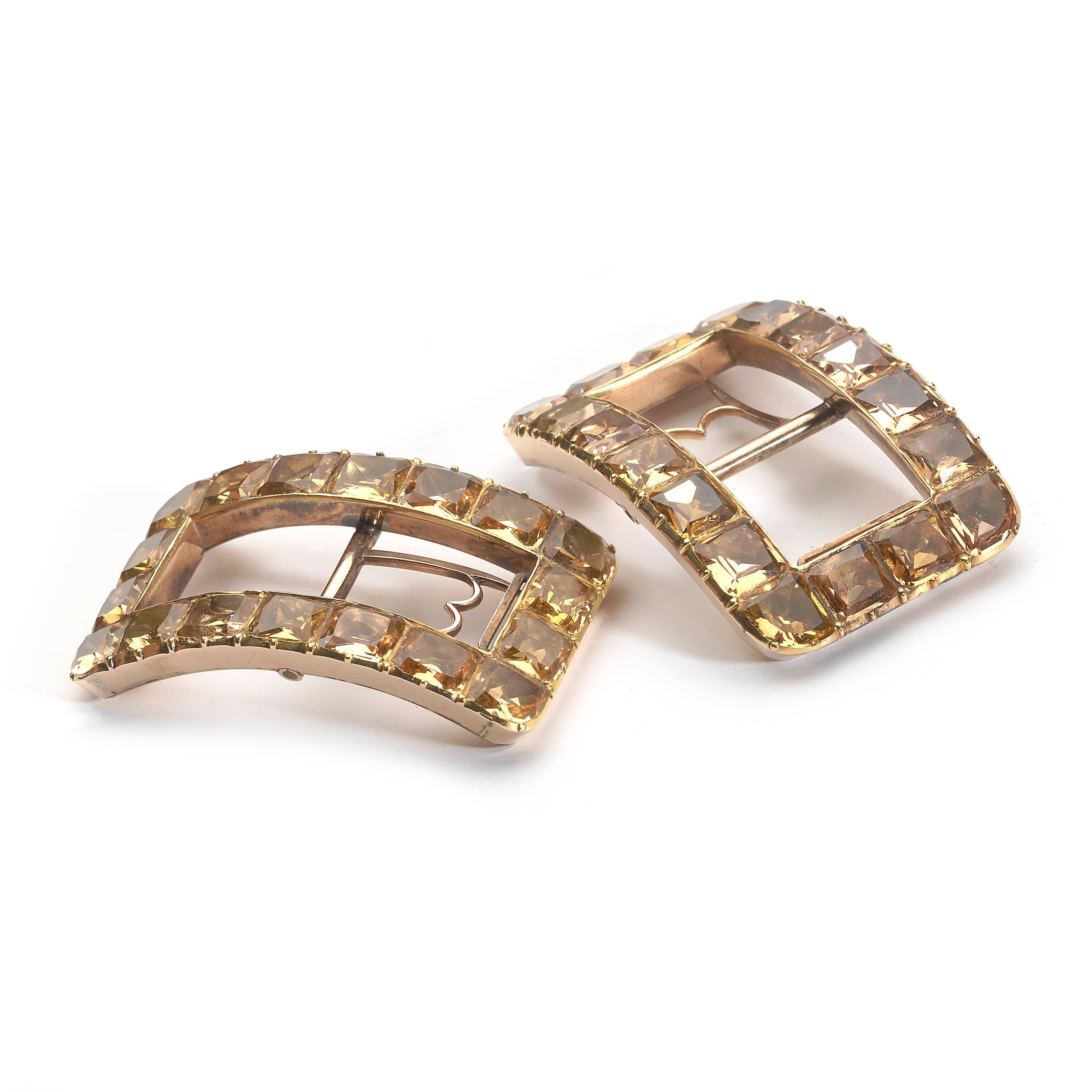 A pair of George III topaz and gold shoe buckles, set with cushion cut foil backed topaz, with cut down settings forming the outer, curved, rectangular frame, with a flat inner edge and closed back. The fittings have two row tongues with double hoop