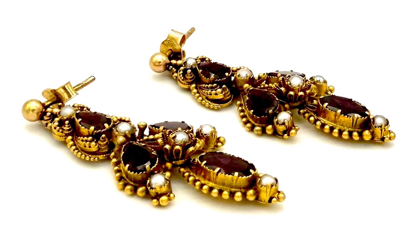 These antique late Georgian dangle earrings were created in the 1830`s out of 14K gold. Each earring is made up from three articulated segments. Each earring is set with four different cut garnets and six natural pearls in different sizes. There are