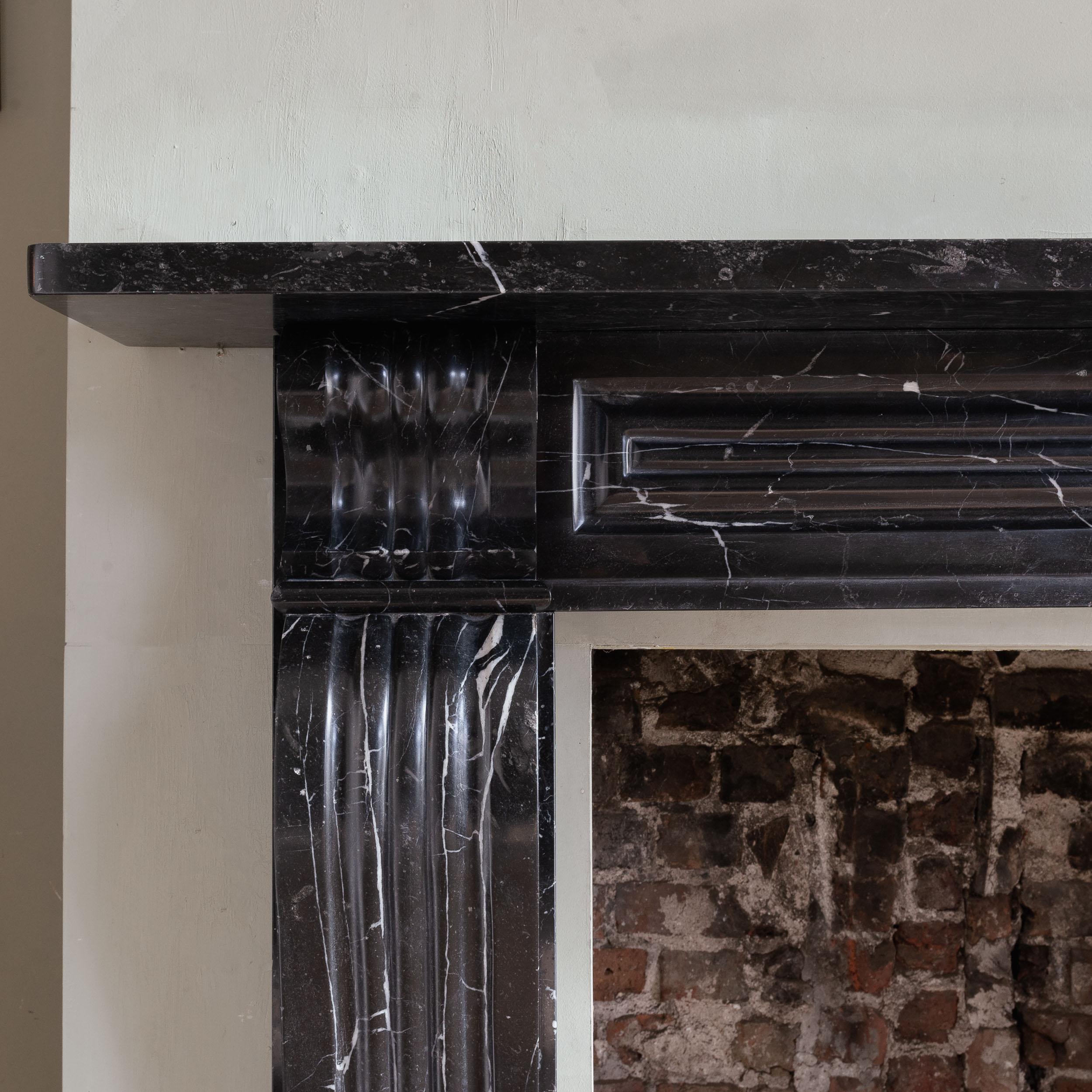 George IV Radstock Black fireplace, c.1820s, the panelled frieze with shaped corbels to each corner, the boldly scrolled and moulded console jambs on block feet. One of a near pair.

Dimensions:	118.5cm (46¾