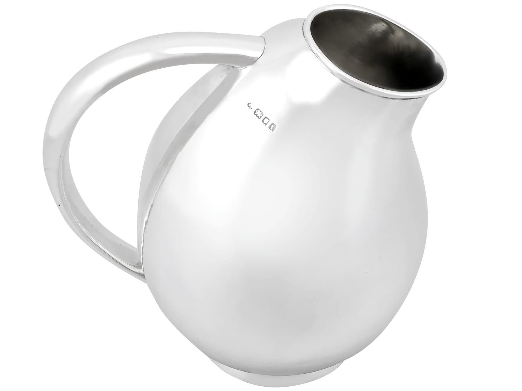 An exceptional, fine and impressive antique George V sterling silver jug in the Design style; part of our dining silverware collection.

This exceptional sterling silver jug has a plain asymmetric baluster form onto a circular collet foot, in the