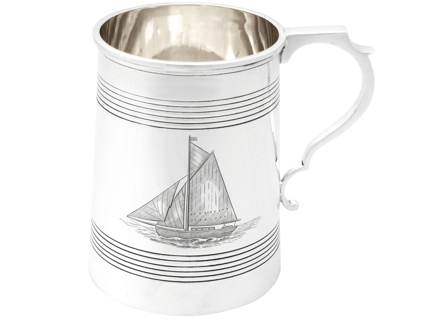 A fine and impressive antique George V English sterling silver pint mug with sailing interest; an addition to our nautical themed silverware collection.

This impressive antique George V sterling silver pint mug has a plain tapering cylindrical