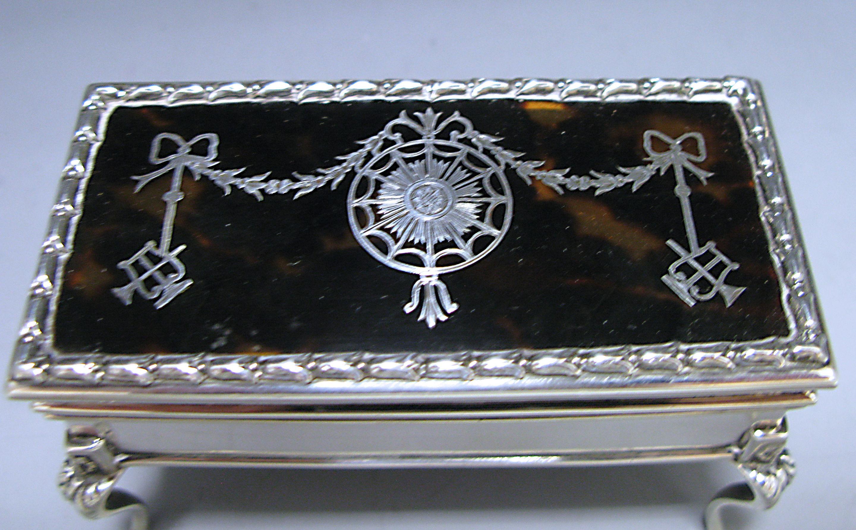 An impressive antique George V silver and tortoiseshell trinket / jewelry box, of rectangular form. The hinged lid has an impressive tortoiseshell panel ornamented with silver pique work depicting bows, swags and a cupid lyre. The box is supported
