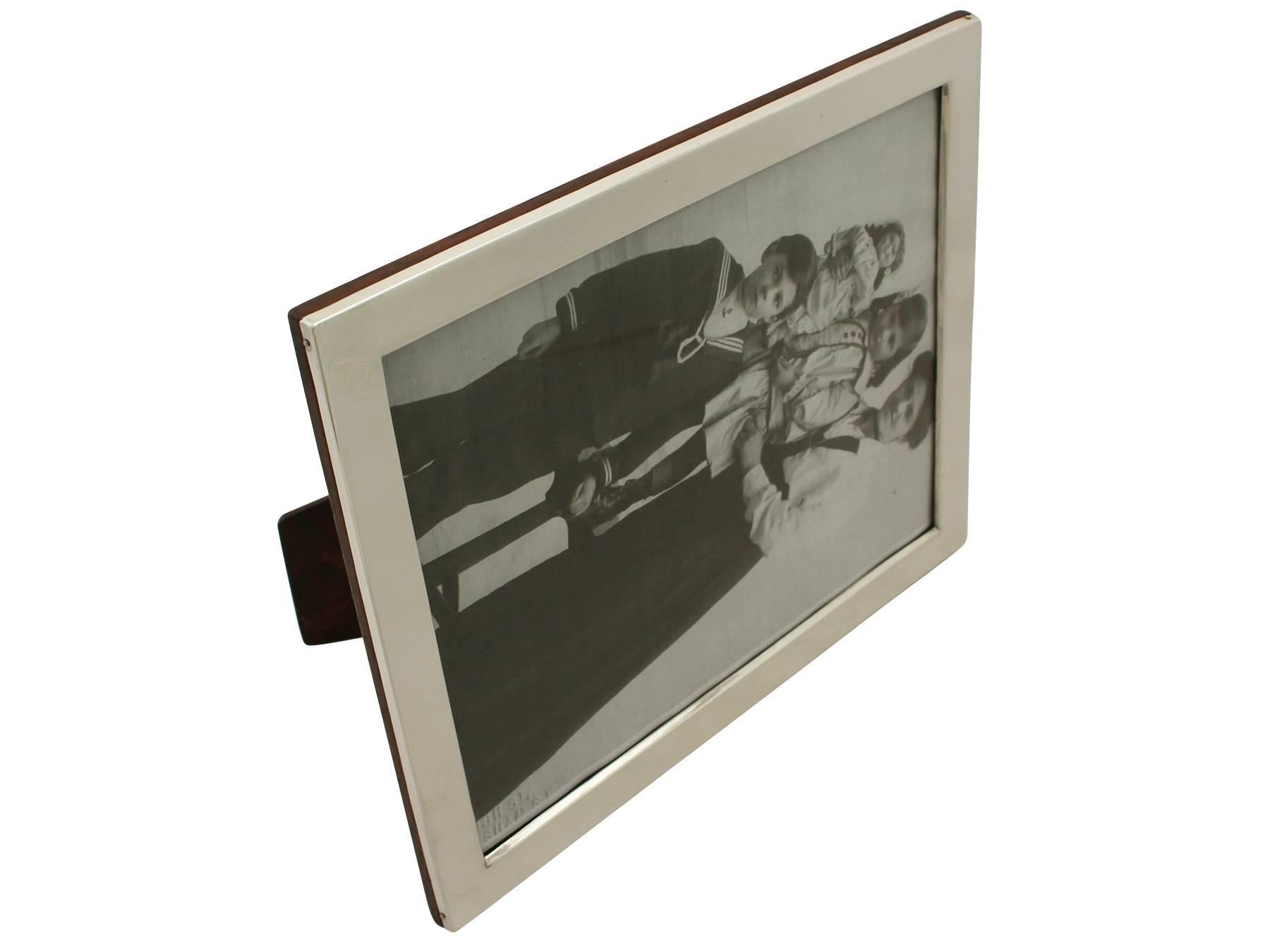 A fine and impressive, large antique George V English sterling silver photograph frame; an addition to our collection of ornamental silverware.

This fine antique George V sterling silver photo frame has a plain rectangular form.

The surface of