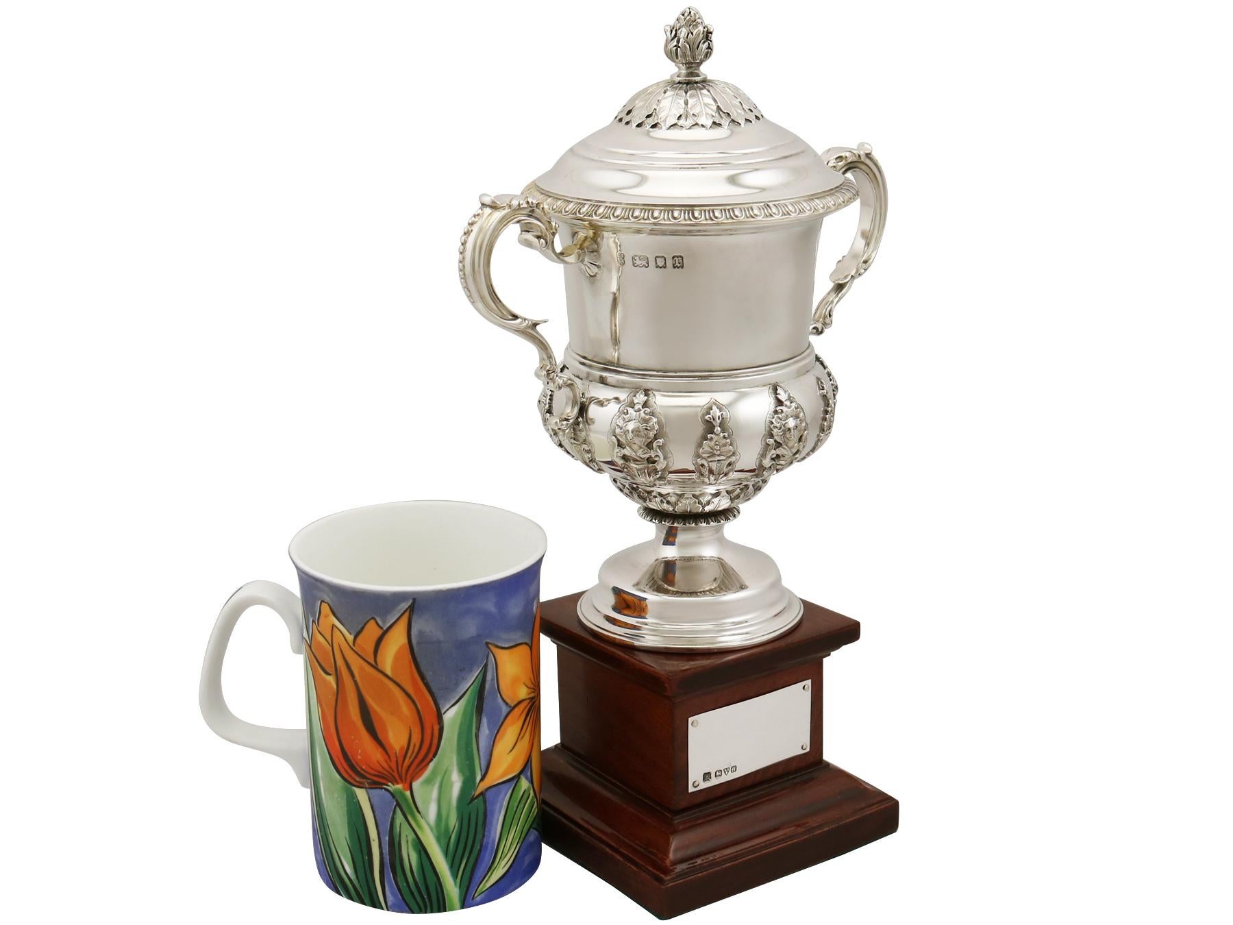 An exceptional, fine and impressive antique George V English sterling silver presentation cup with cover and original plinth; an addition to our presentation silverware collection.

This exceptional antique sterling silver trophy cup with stand