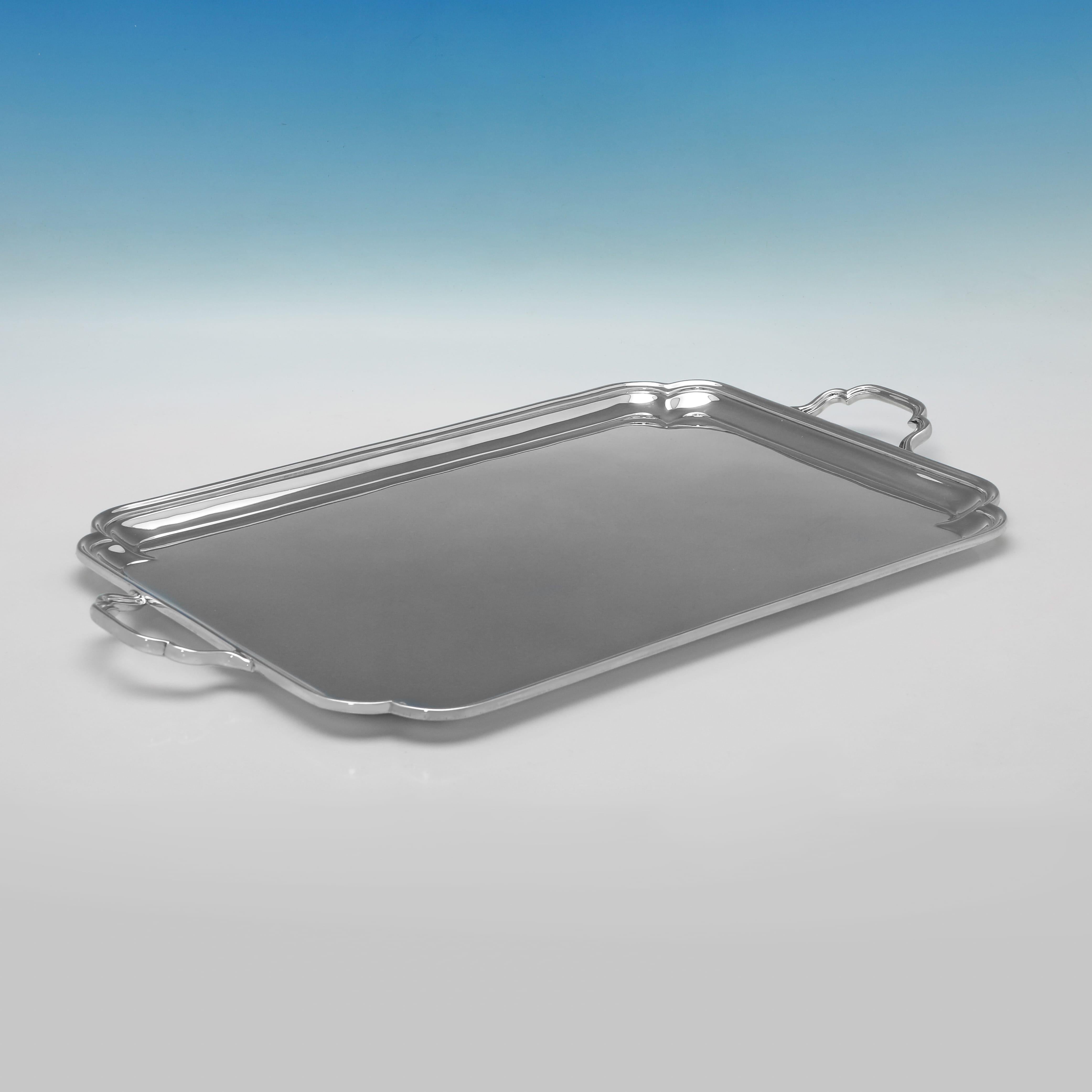 Poinçonné à Londres en 1910 par Goldsmiths & Silversmiths Co., cet élégant plateau ancien en argent sterling de style George V présente des coins façonnés, des poignées appliquées et une bordure cannelée. Le plateau mesure 3,5 cm (1,25