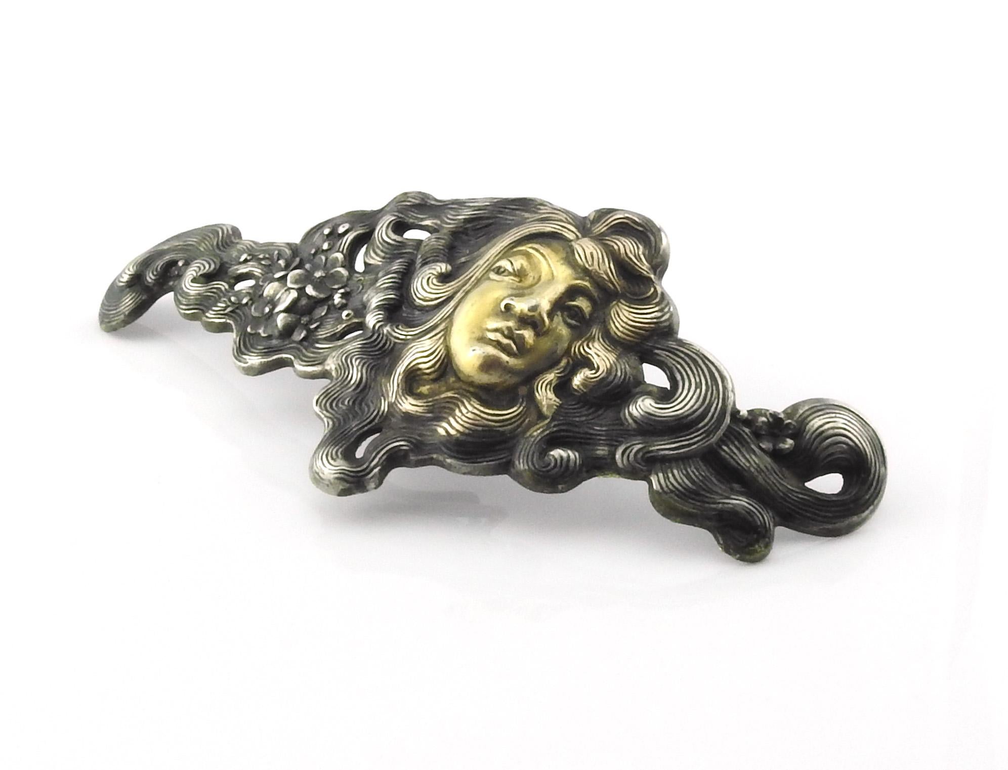Antique George W. Shiebler sterling silver and 14K gold belt buckle.

George W. Shiebler & Co pf NY, NY sterling silver pierced and chased buckle featuring a woman's face in gold relief with flowers in her flowing hair. Circa 1890

Measures 5