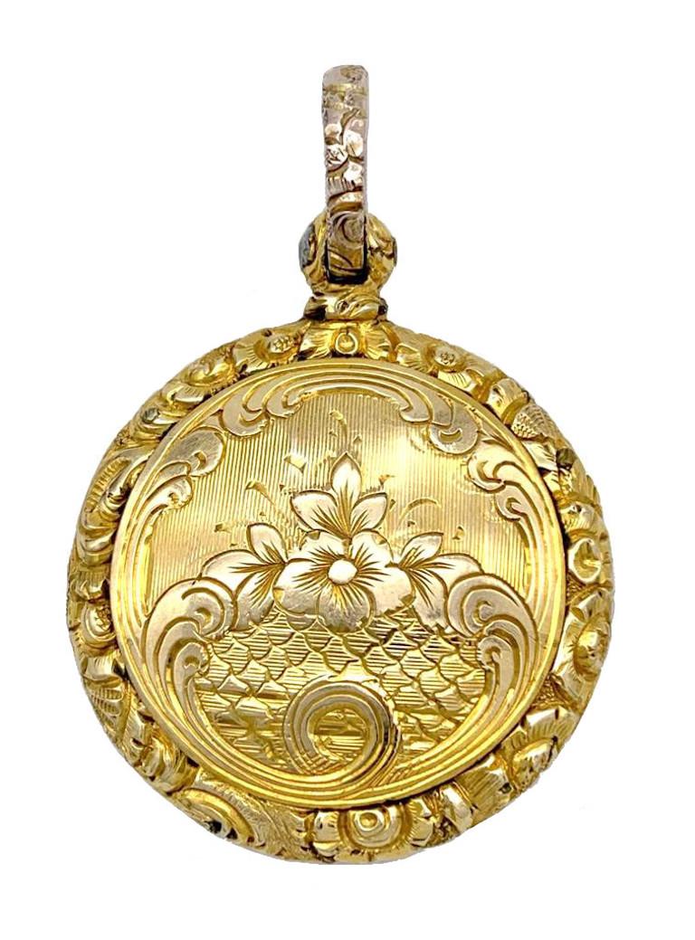 This finely chiselled and engraved Georgian 15 karat gold locket pendant holds a beautiful hair arrangement under glass in the shape of feathers. The two colour hair locks are held together by gold wire.