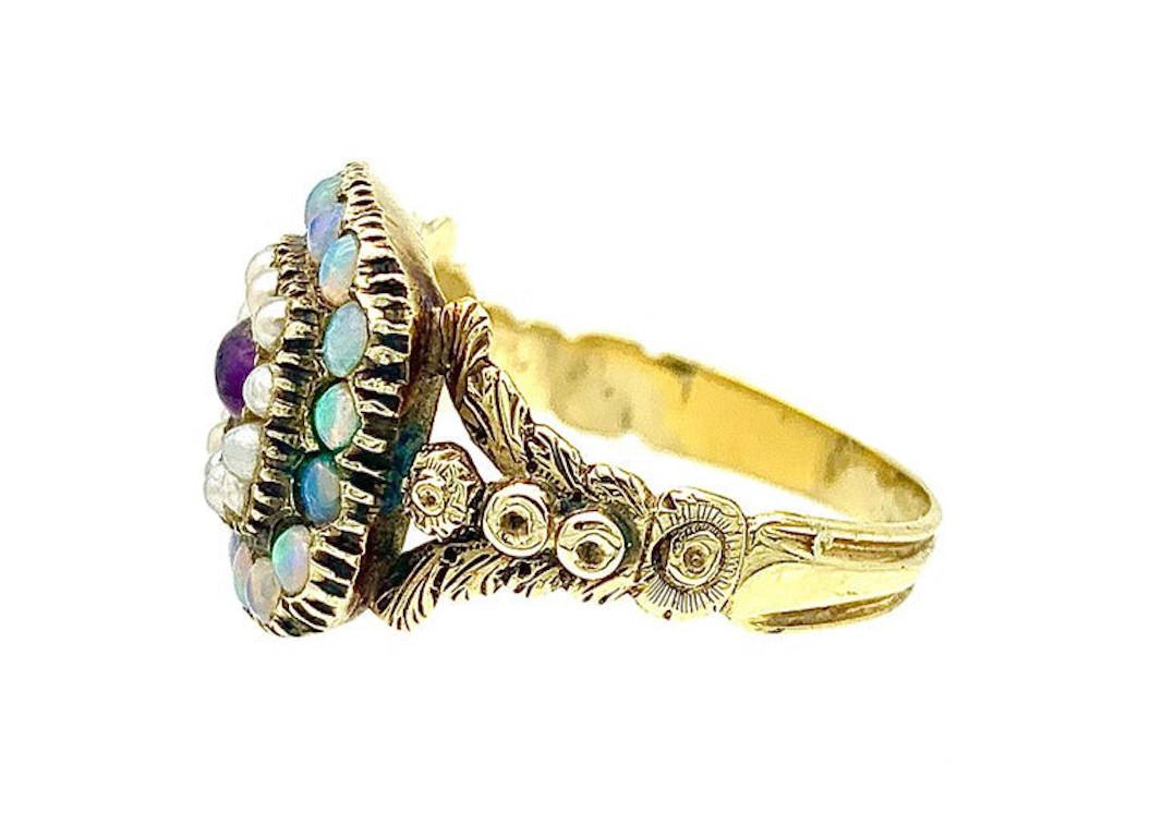 This delightful little Georgian 15 karat gold ring dates from 1825 ca. It is set with cabochon amethyst within a natural pearl surround and an outer frame of cabochon cut opals. 