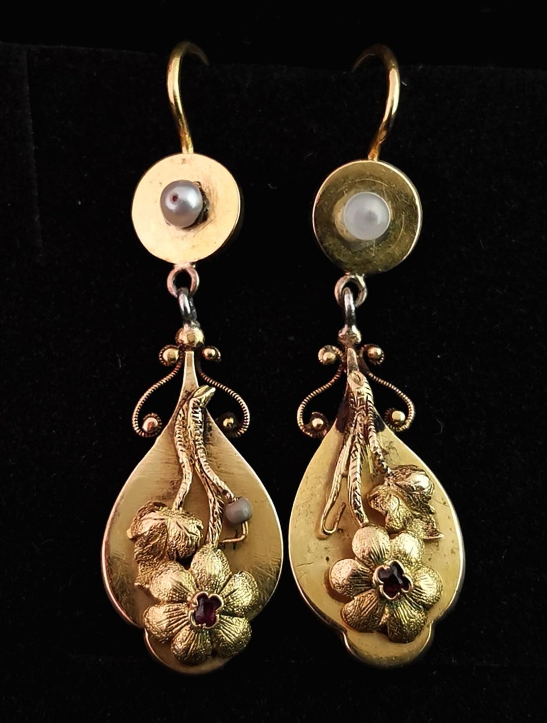 A gorgeous pair of Antique late Georgian gold drop earrings.

They have a stunning teardrop shaped lower half that has intricate applied gold flowers each set with a Ruby, the drops feature delicate tendrils and leafs.

The main drops are suspended