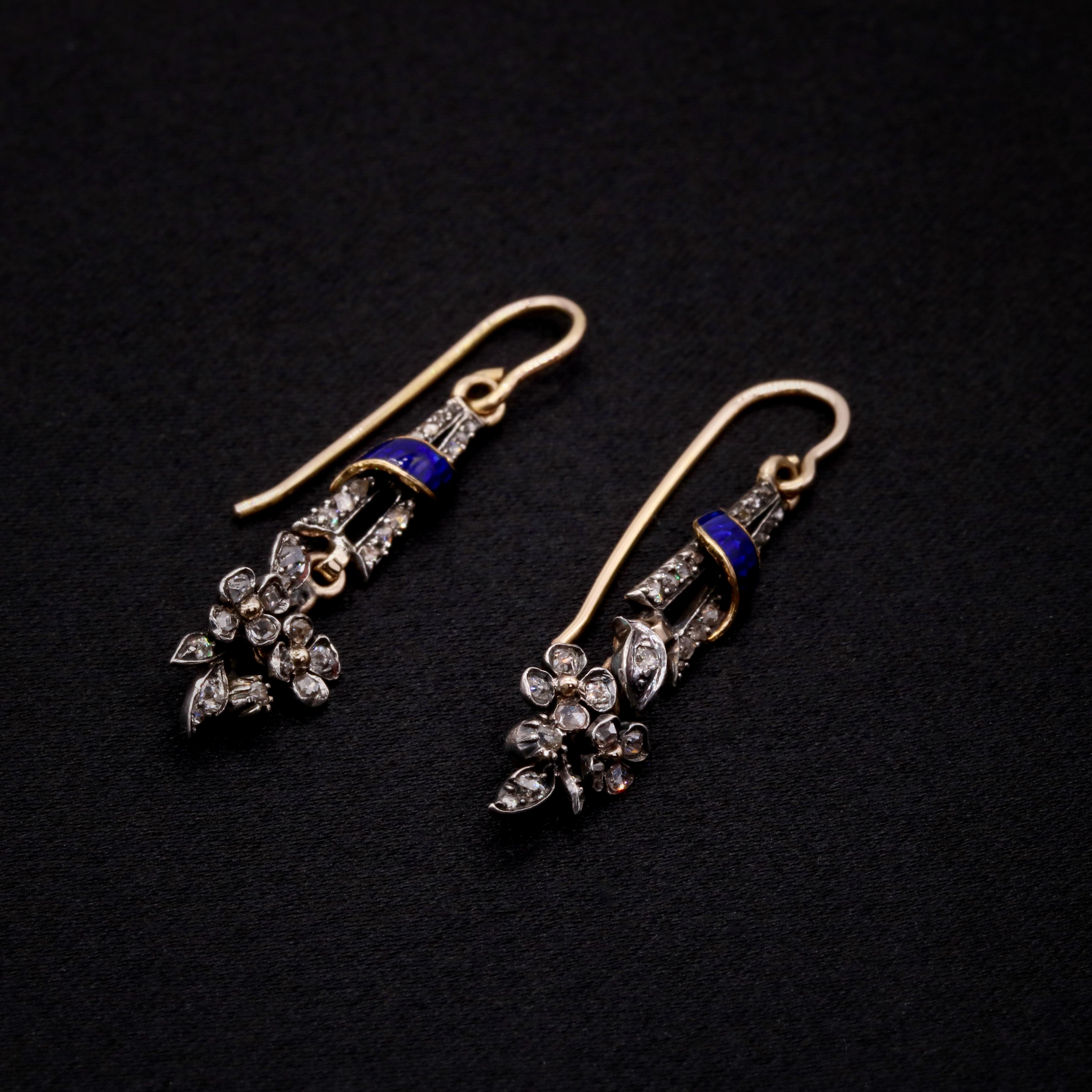 A pair of diamond, enamel, silver and yellow gold earrings, each comprising twenty-nine rose cut diamonds, a panel of blue enamel, set in silver, backed in 18 karat yellow gold, with 18 karat yellow gold fittings. 

These delicate earrings are