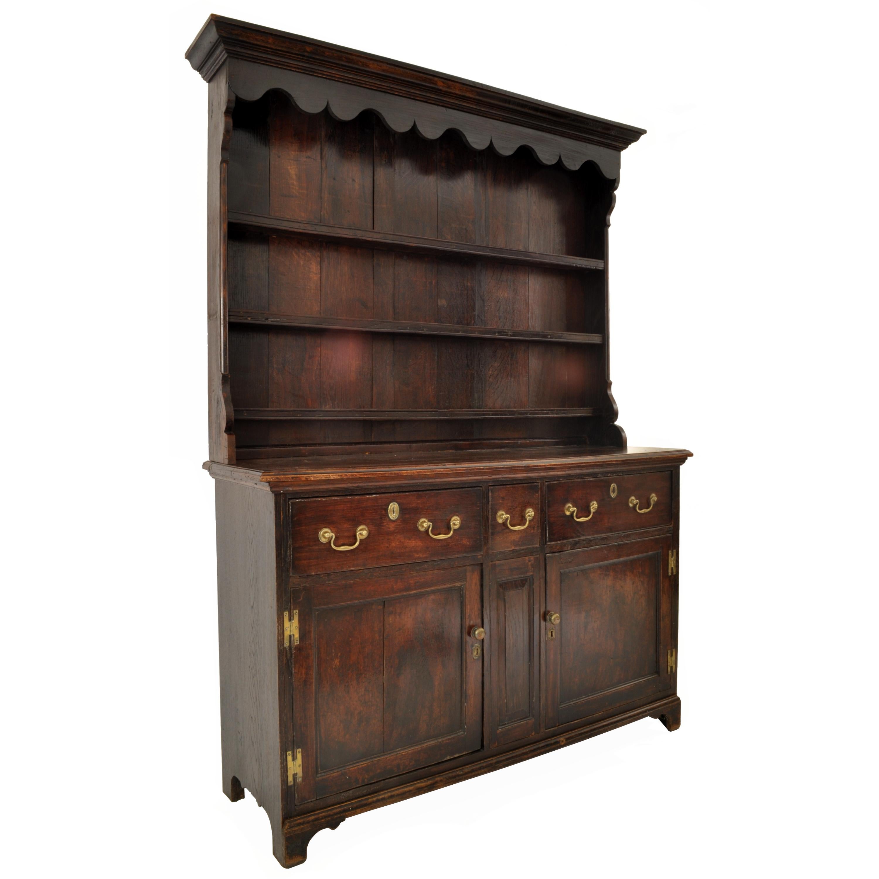 A good and diminuitive George III oak & elm dresser/cupboard, Circa 1780.
This dresser is in unusually period condition, with original finish and color. Thre dresser having a stepped cornice to the pot rack with a shaped apron below and three