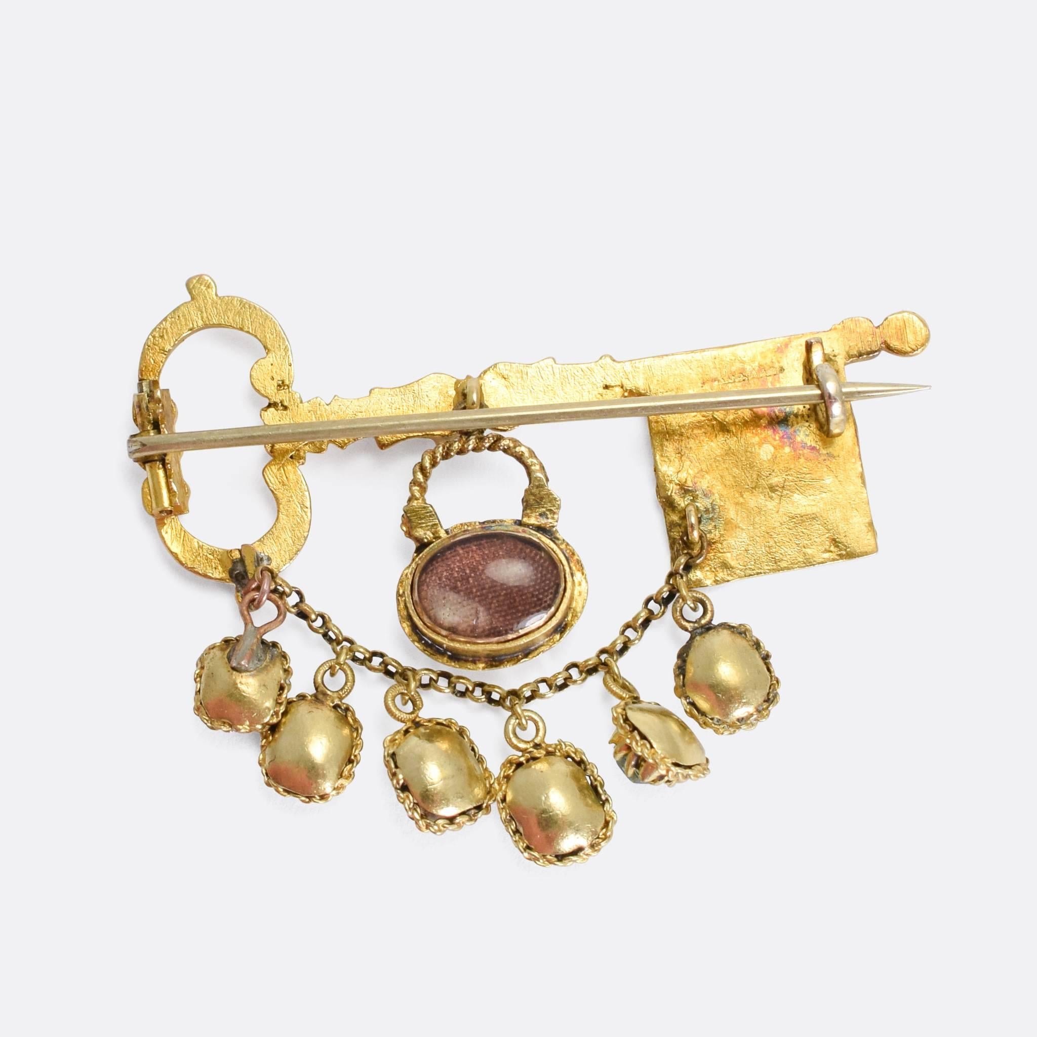 A spectacular, Museum quality, acrostic brooch dating from the early 19th Century. The main body is a beautifully hand-chased gold key, featuring intricate cross-hatched patterns and foliate details. Dangling from the key are two further components: