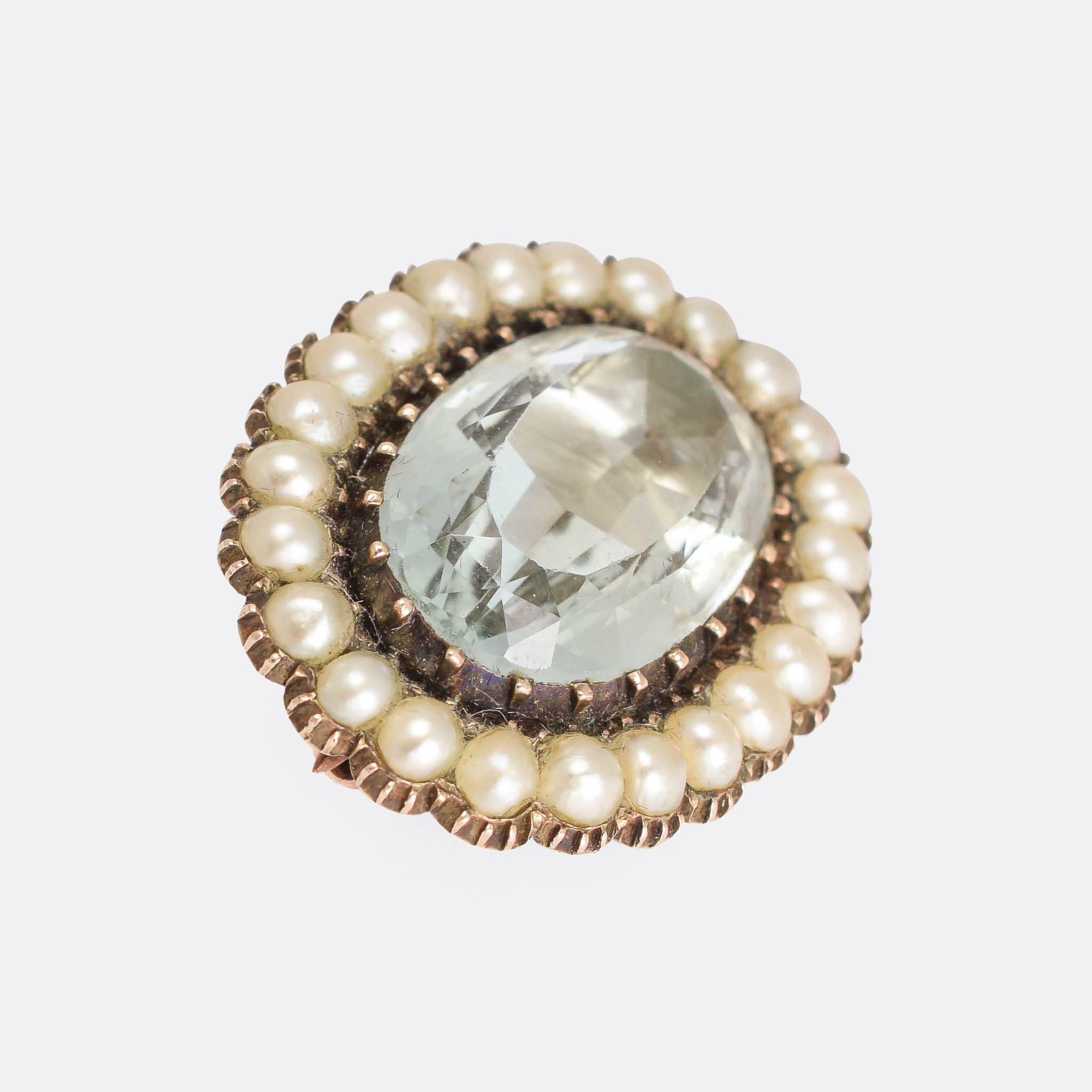 A gorgeous Georgian brooch set with with a lovely combination of stones: a principal faceted aquamarine within a halo of natural pearls. The aquamarine is foil-backed, making it glow brightly in the light. Modelled in 15k gold throughout, the piece