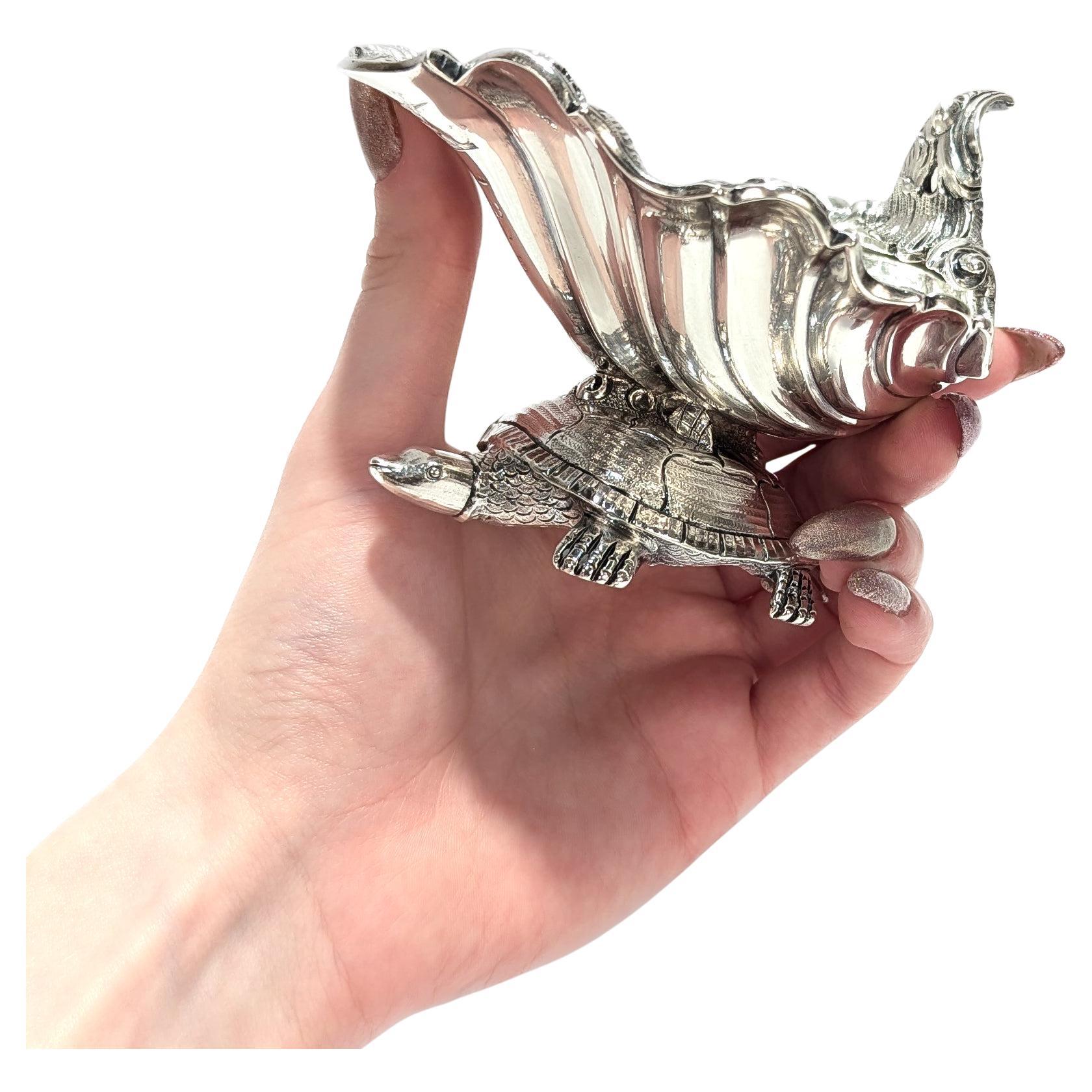 A fine signed English George III salt cellar or sweetmeat dish.

In sterling silver.

By Thomas & Joseph Guest and Joseph Cradock, London. 

Dated for 1807.

In the form of a turtle with an open seashell resting on its back. The seashell a rocaille