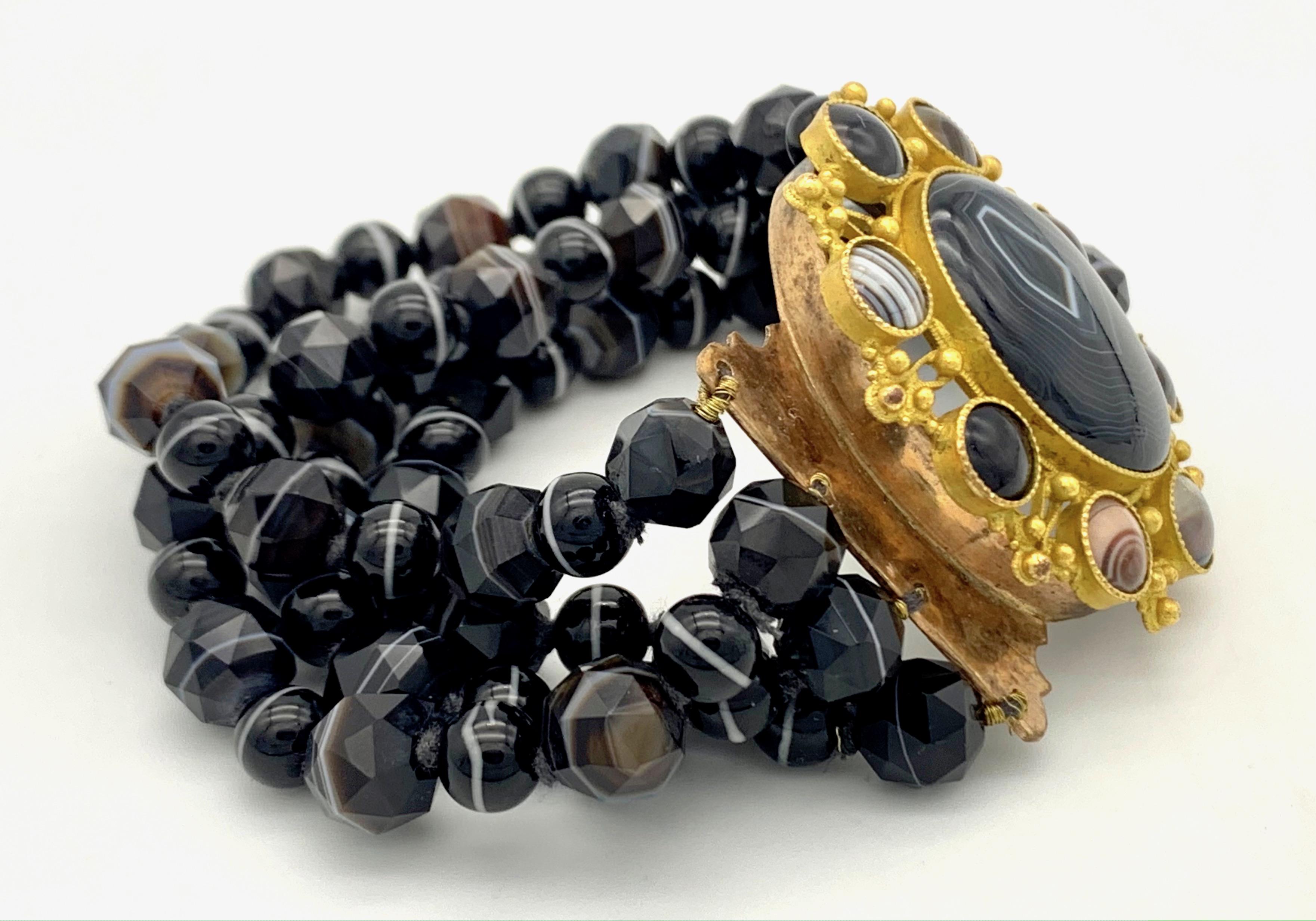 This stylish banded agate bracelet made up from 4 rows of fine agate beads comes with a beautiful clasp executed in gilt metal and Pinchbeek around 1830.