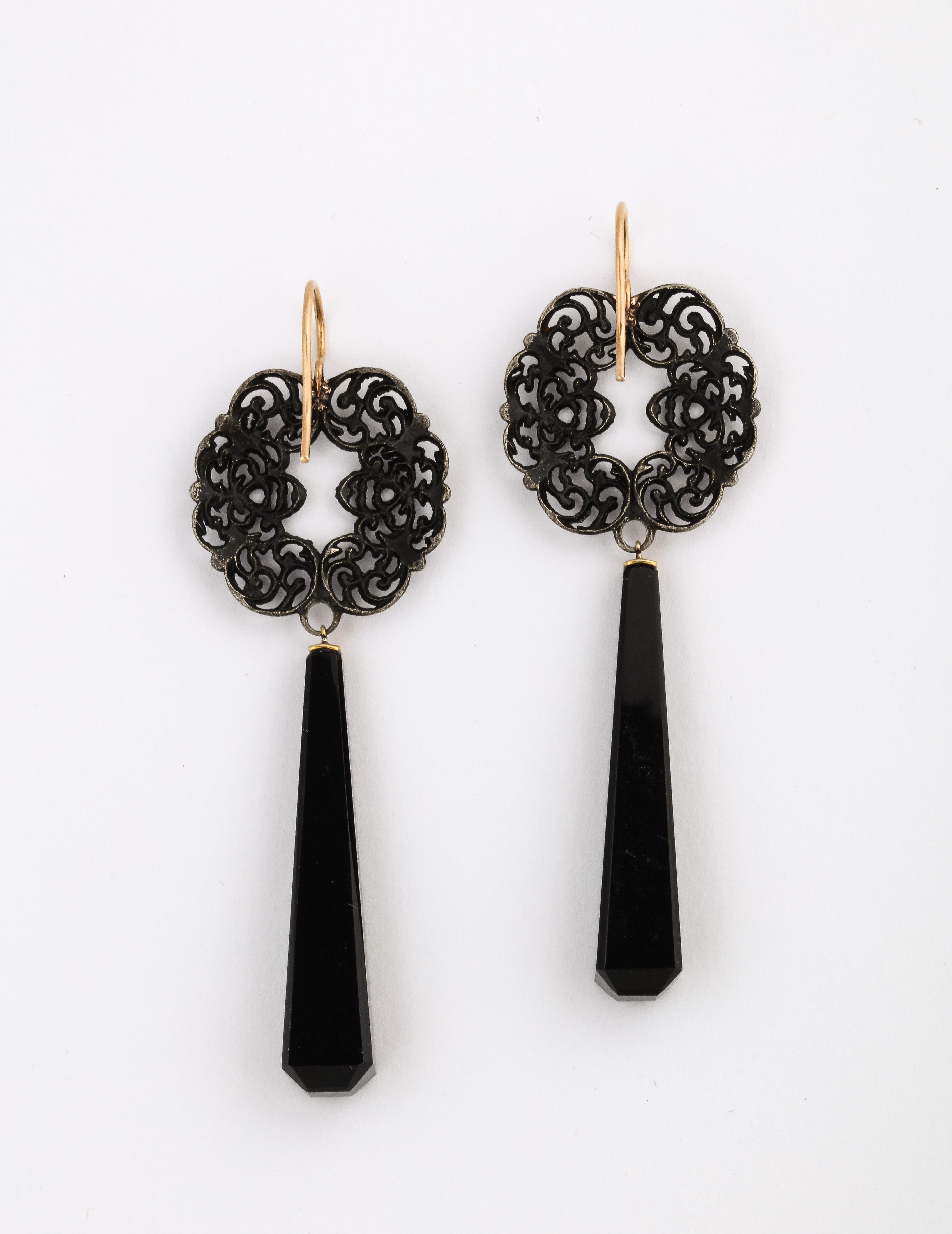 Exotic Geiss round, scrolling vines are the top section of these Berlin Iron earrings c. 1820. We added the onyx pyramids, thereby creating a pair of romantic and very lovely chandelier earrings , light on the ear and uniquely beautiful. 
During the