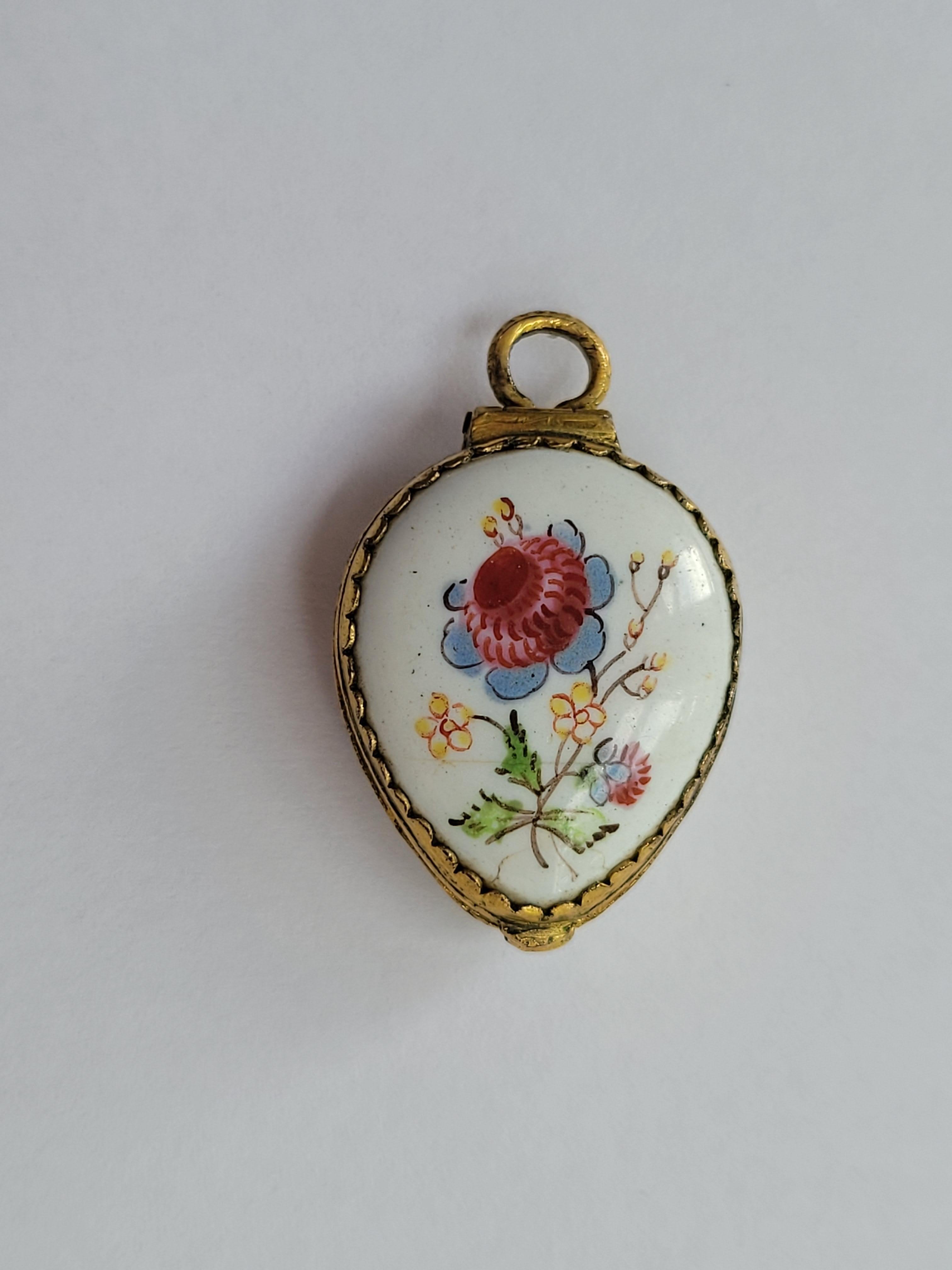 Dieses bezaubernde georgianische Medaillon aus der Zeit um 1800 aus Bilston Battersea mit handgemalter Emaille ist ein seltenes und fesselndes Sammlerstück mit tiefen englischen Wurzeln. In Herzform gefertigt und mit traditionellen floralen Motiven