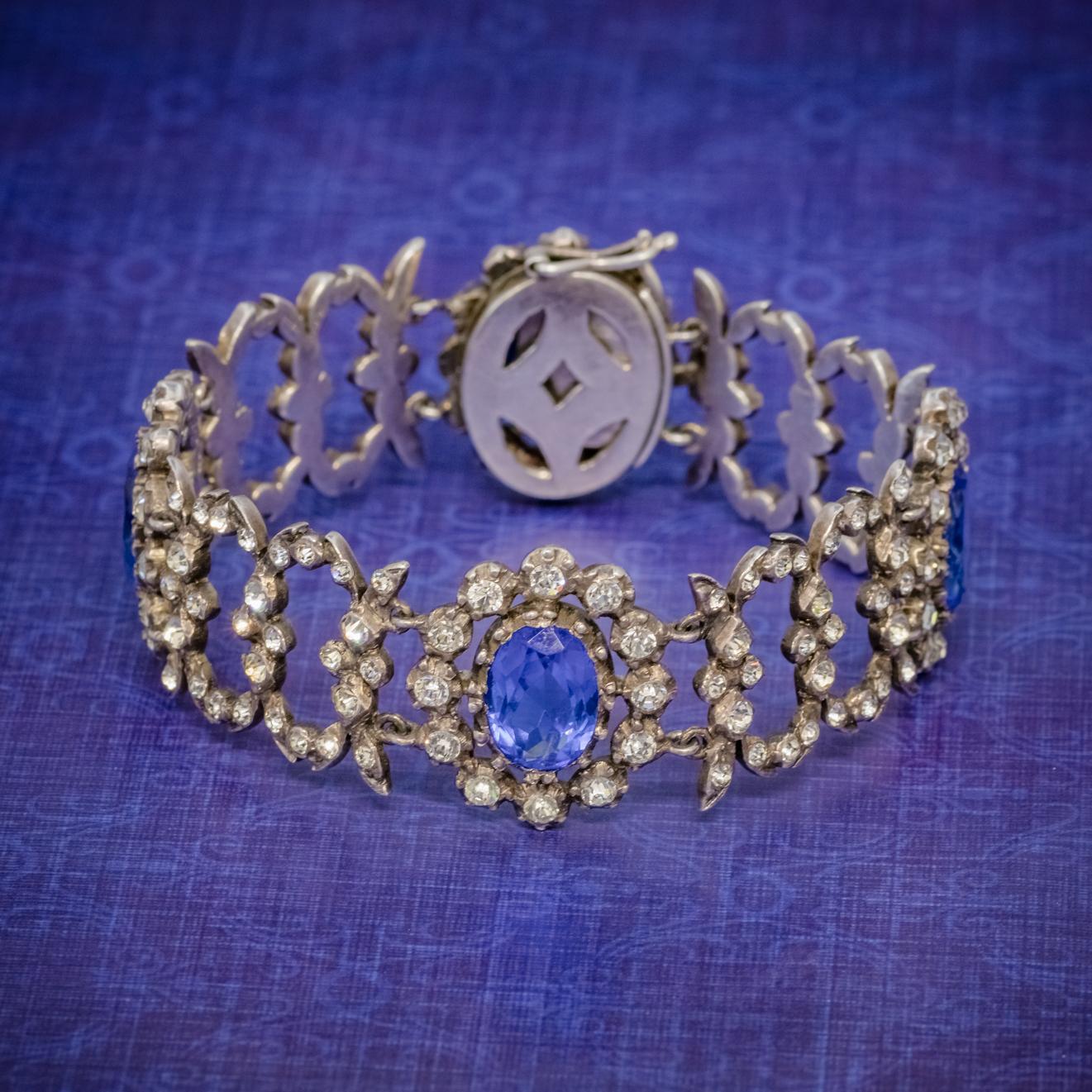 An exquisite Antique Georgian bracelet made up of ornate, solid Silver links decorated with four large blue Paste Stones and an array of glistening white Pastes.

Paste is a transparent flint glass that simulates the fire and brilliance of