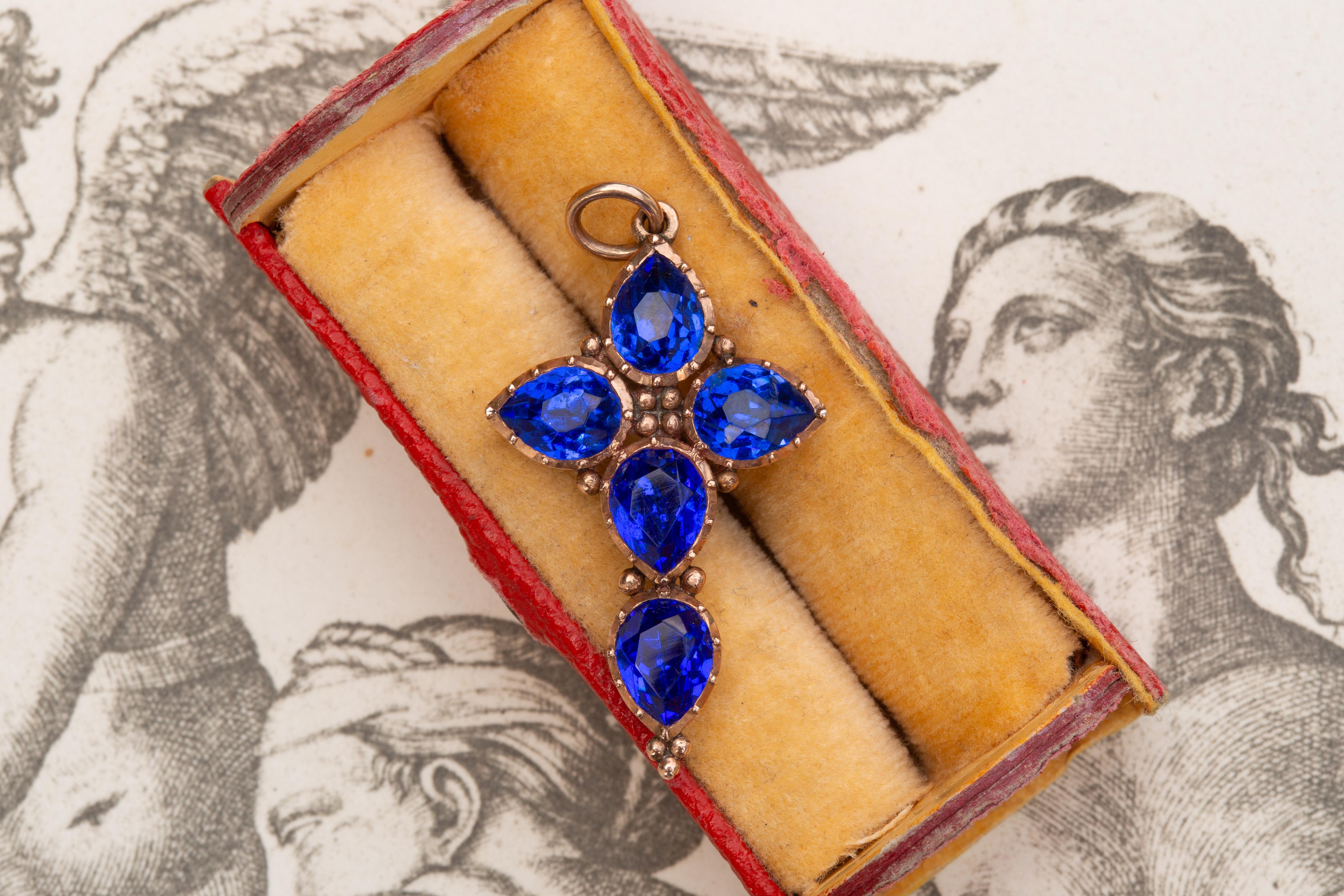 This striking antique Georgian blue paste cross pendant dates to around 1810. It is crafted in 15K rose gold and remains in truly exceptional condition despite its significant age. The beautifully faceted and foil-backed pastes display a luminous