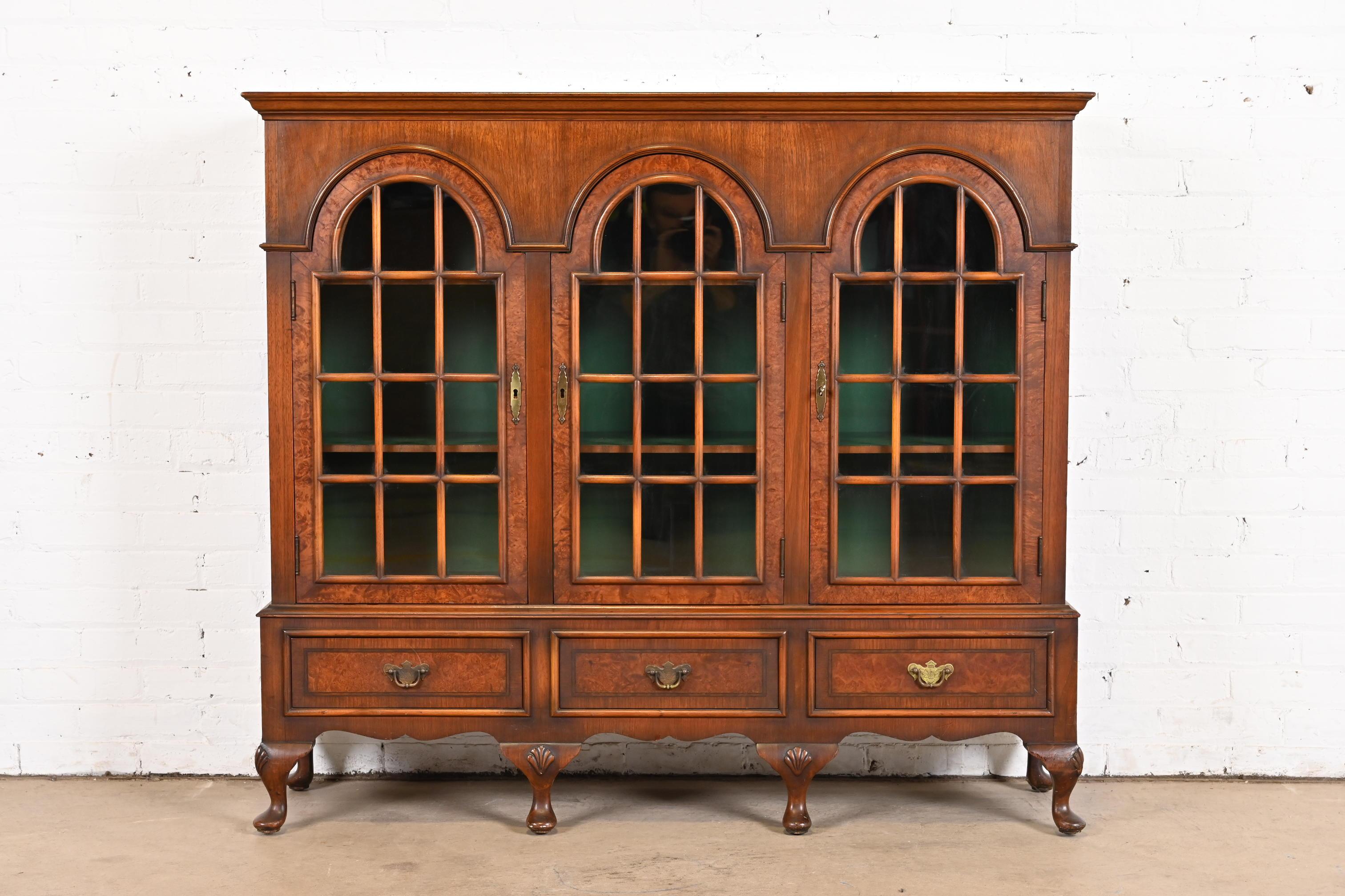 A beautiful antique Georgian or Queen Anne style glass front triple bookcase

USA, Early 20th Century

Carved walnut, with burled wood inlay, mullioned glass front doors, green painted interior, and original brass hardware.

Measures: 52