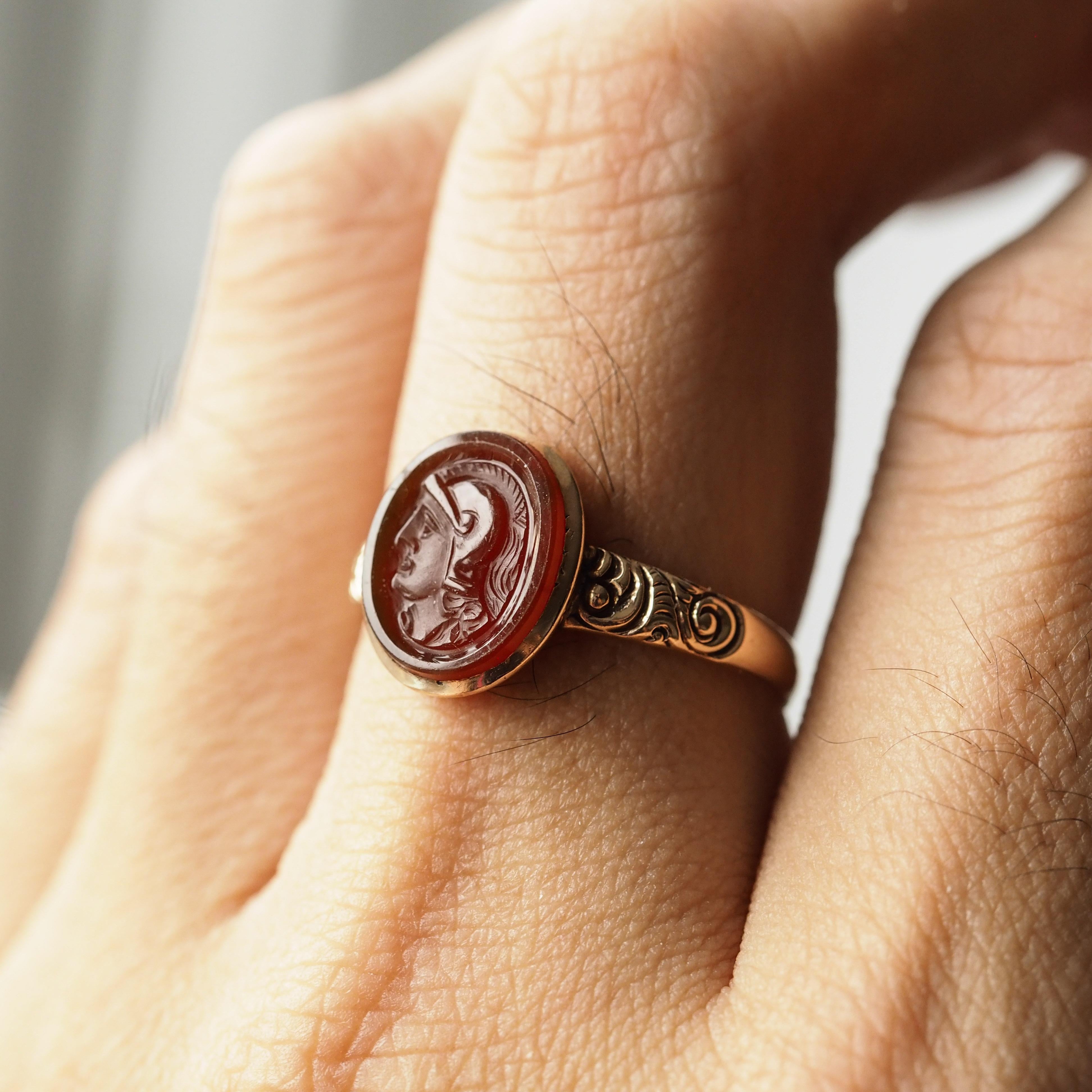 Siamo lieti di offrire questo affascinante anello cammeo antico georgiano in oro 10ct realizzato nel 1820 circa.

L'anello è incastonato con un cammeo centrale in corniola (forse un'incisione precedente) di una figura romana, intricatamente incisa a