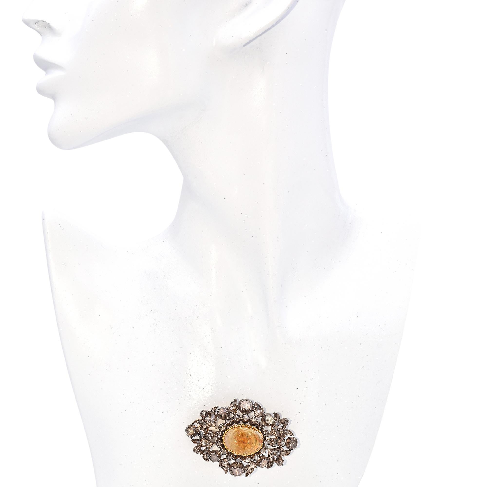 Este exquisito broche georgiano es un testimonio de la maestría artesanal de la época, con un citrino bellamente tallado en su centro, enmarcado por un halo de brillantes diamantes talla rosa. El citrino, con su cálido resplandor dorado, está