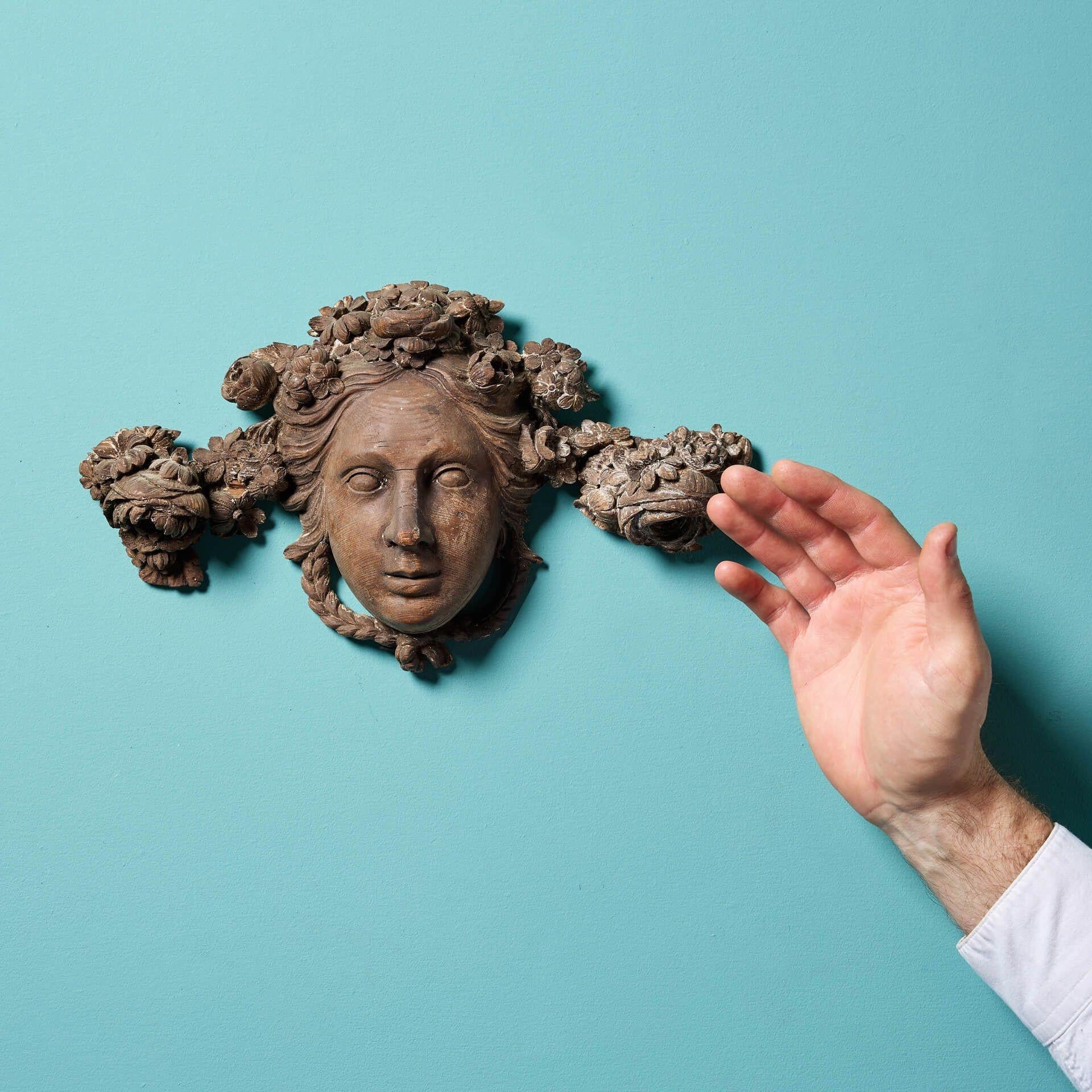 An antique Georgian carved pine wall hanging of a female mask.

This English sculpture would make an intriguing yet striking wall display in any period property.

Crafted in pine, this neoclassical style sculpture depicts a detailed handcarved face