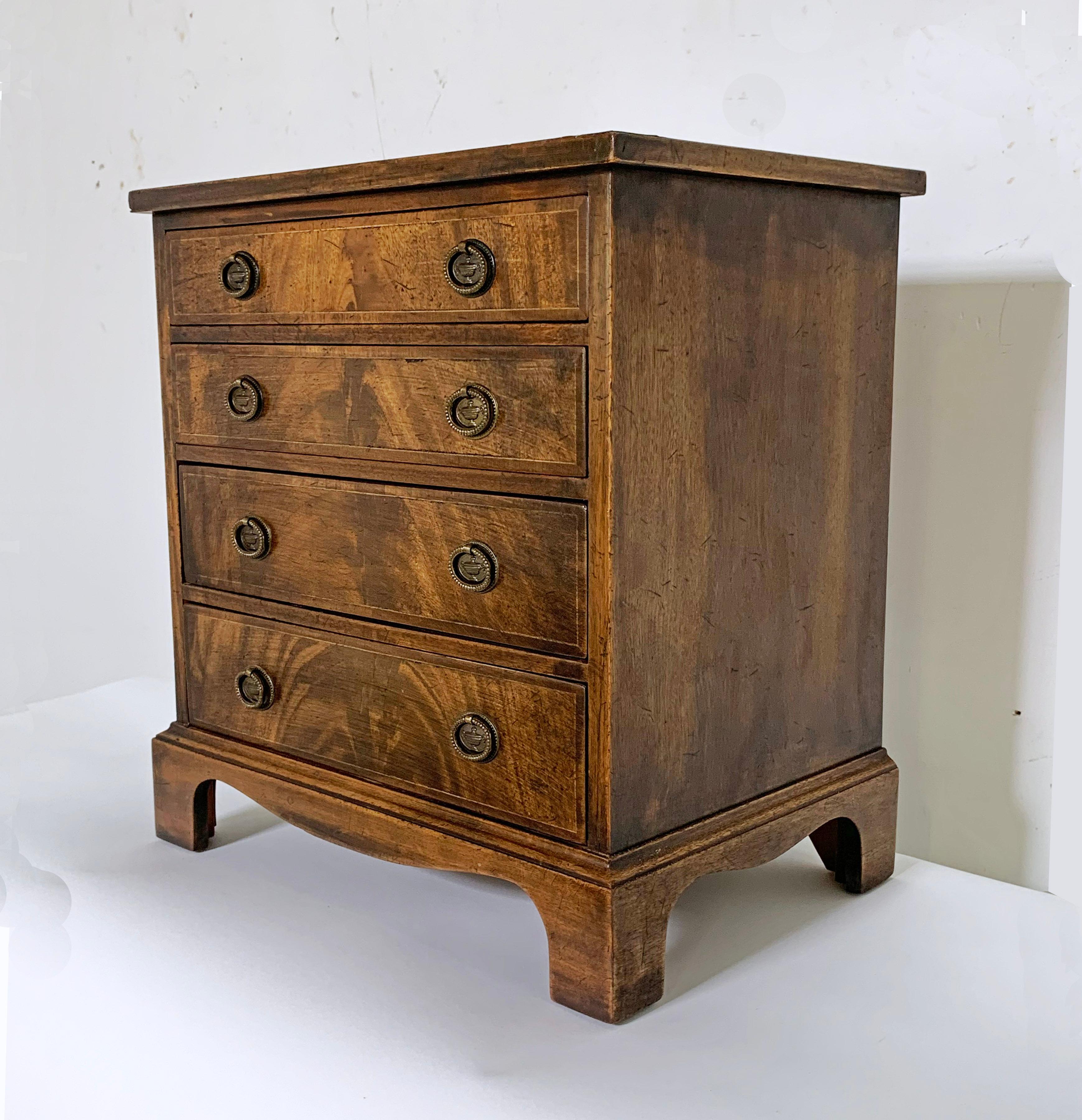 An antique miniature mahogany and elm Georgian child's chest of drawers with boxwood stringing, circa 1780s.